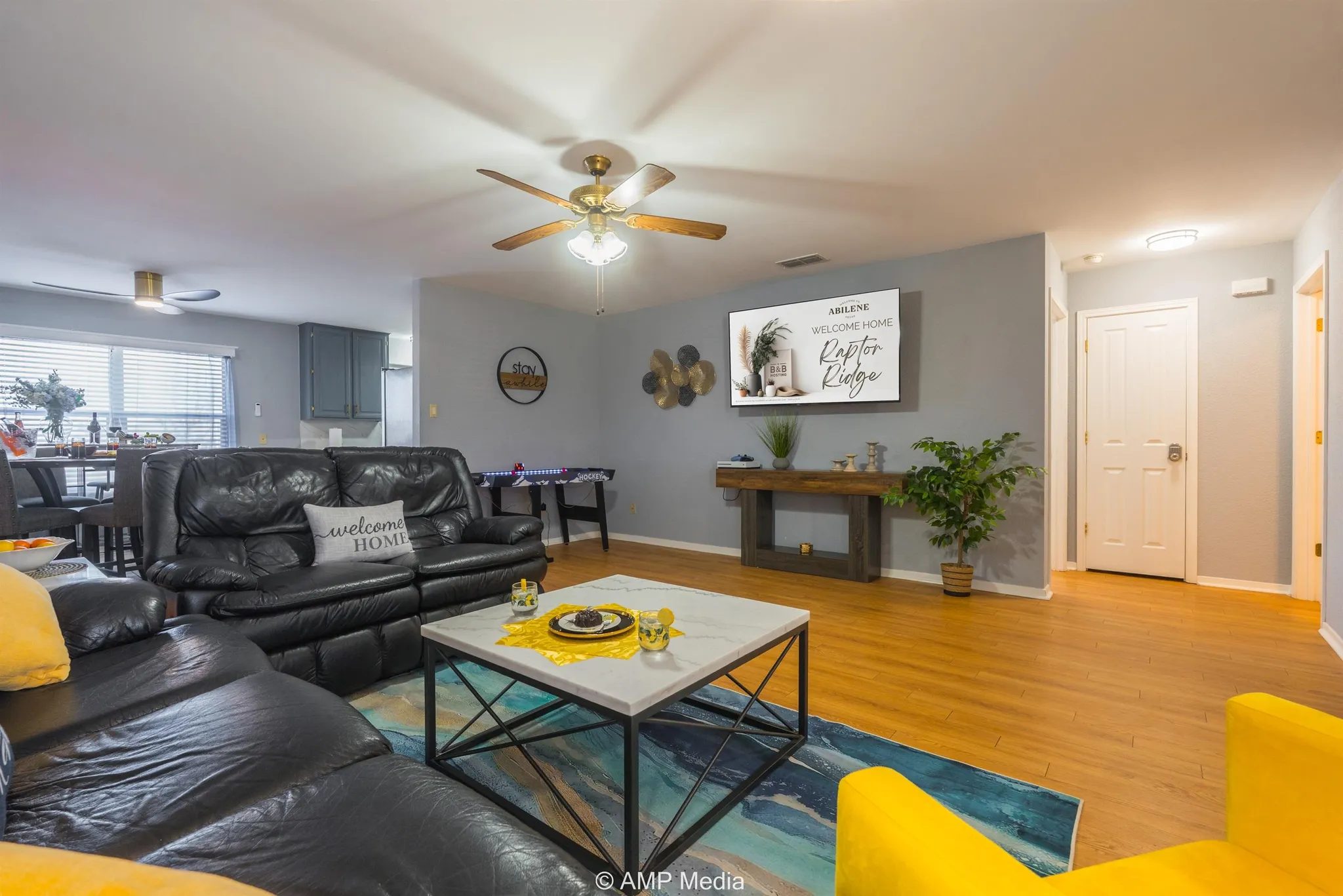 A living room with black leather couches, a coffee table, and a TV.