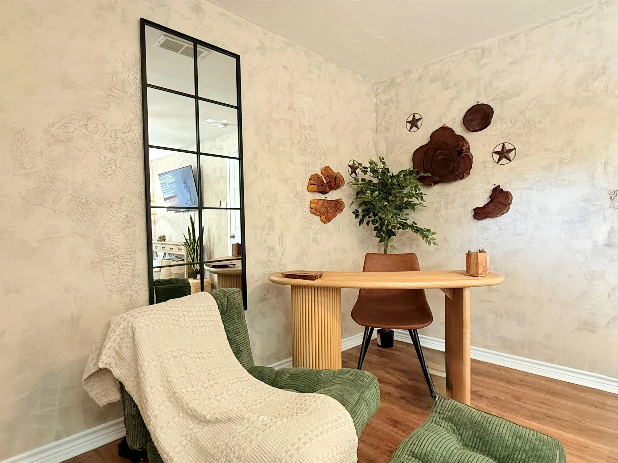 A green corduroy armchair with a cream throw is next to a wooden desk and chair.