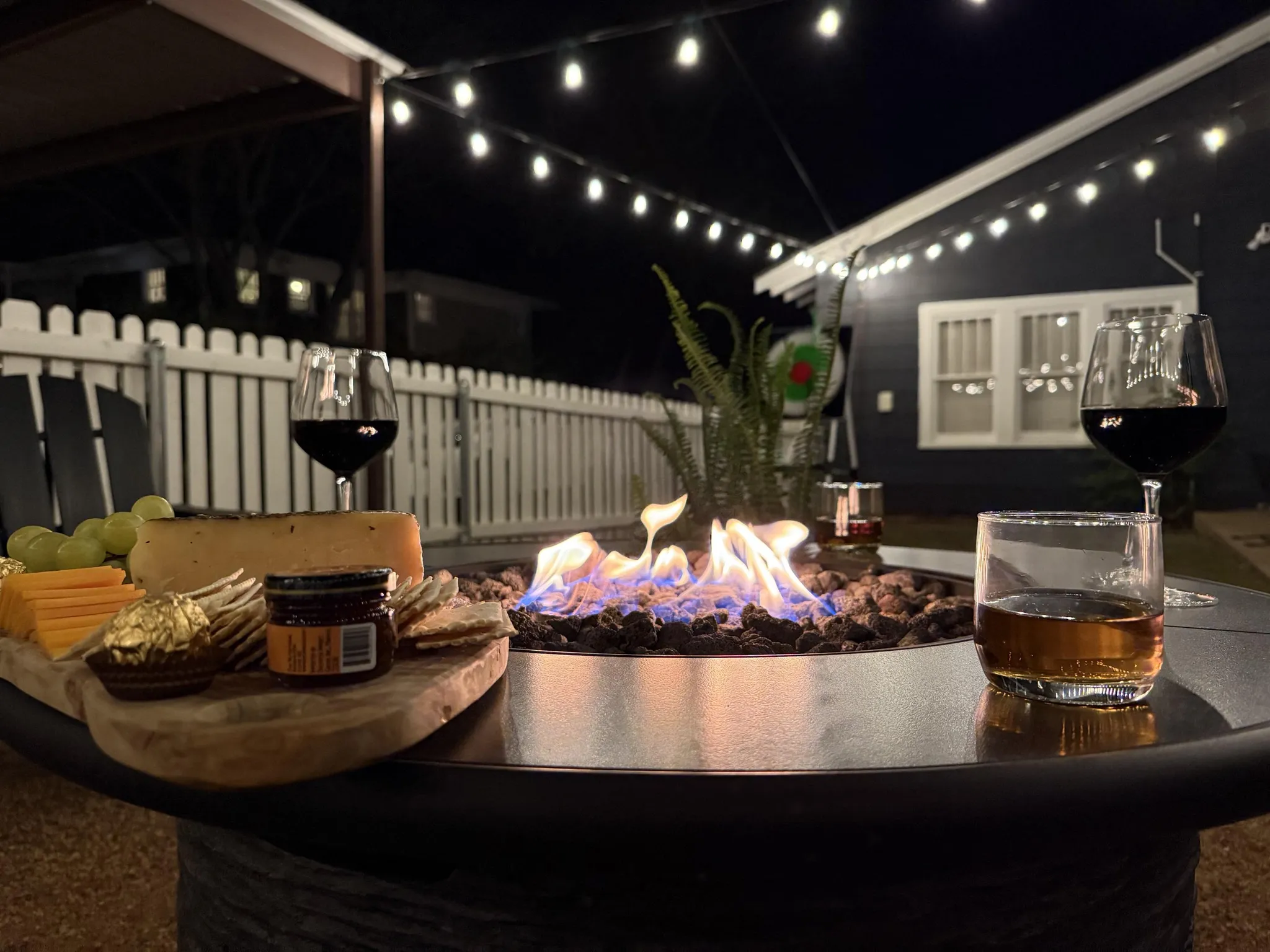 An aerial view shows a blue house with a gray roof, a driveway, and trees.