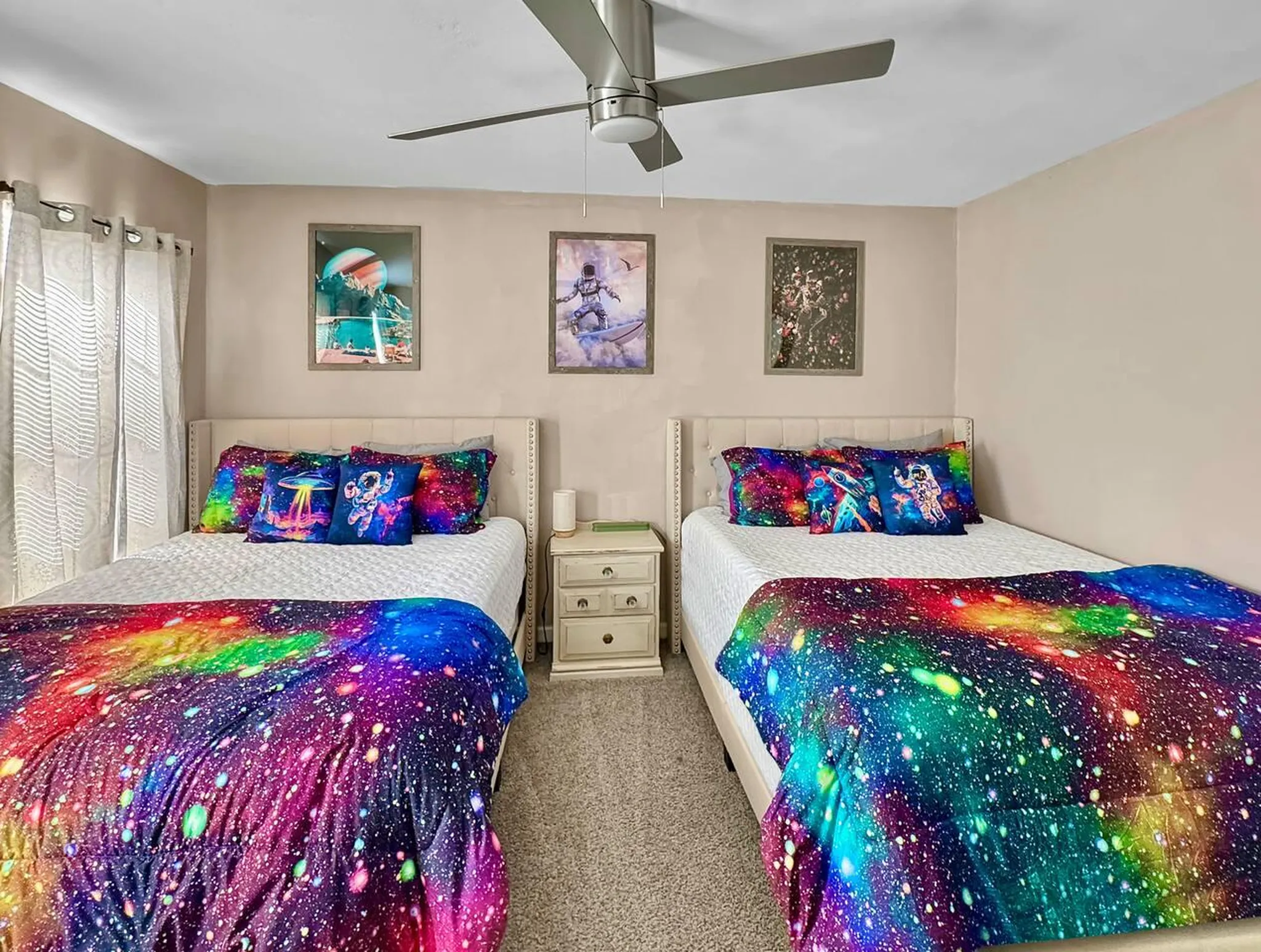 Two beds in a room with colorful bedding, green headboards, and framed art on the wall.