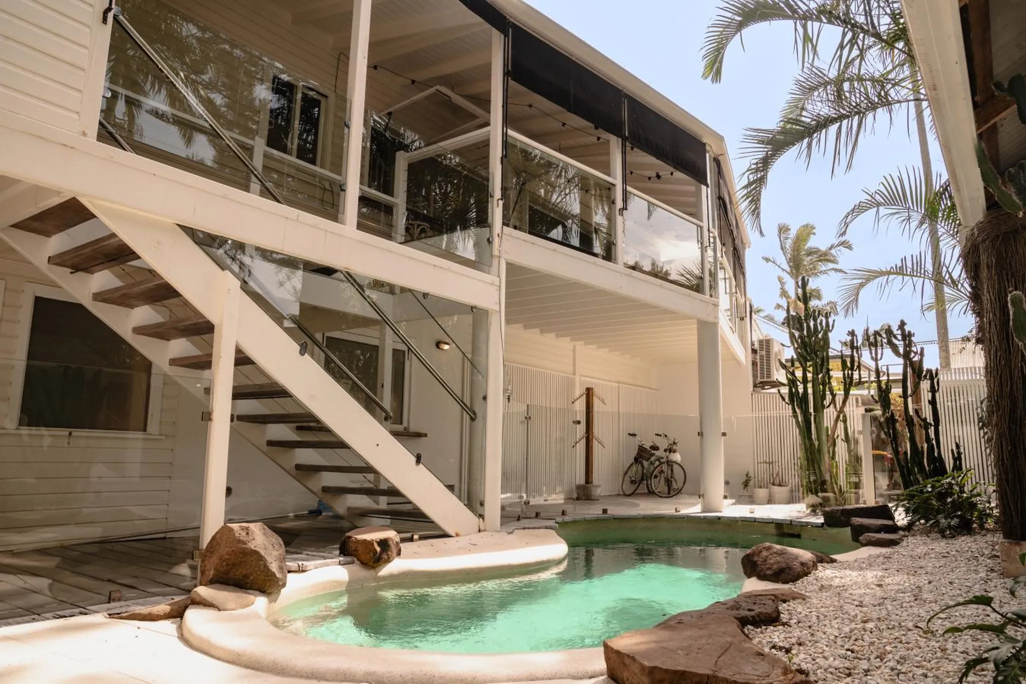Modern white house with outdoor pool, stairs, palm trees and cactuses.
