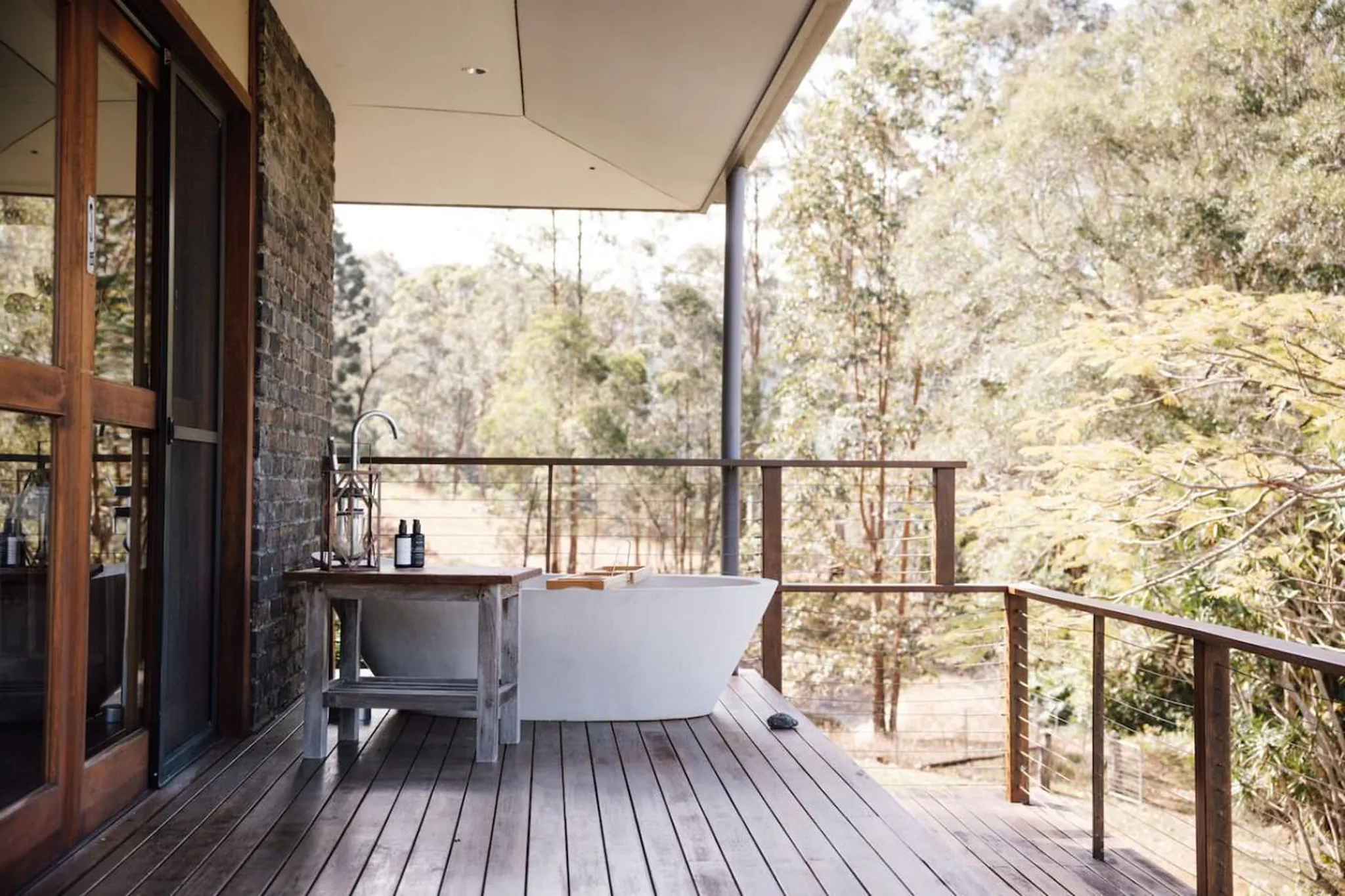 Outdoor bathtub on a wooden deck with trees in the background.