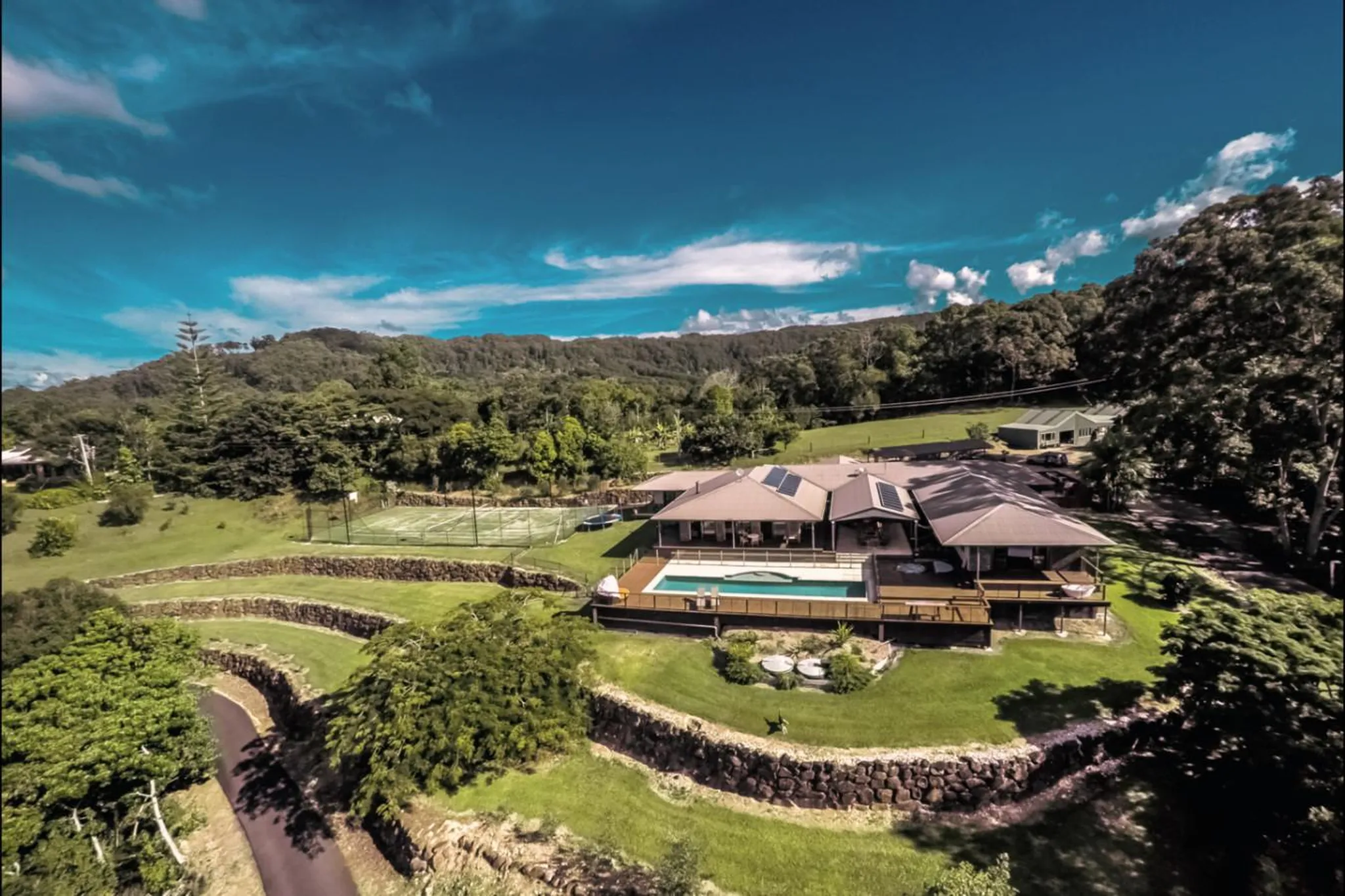 Luxury resort with a pool, tennis court, and lush greenery.