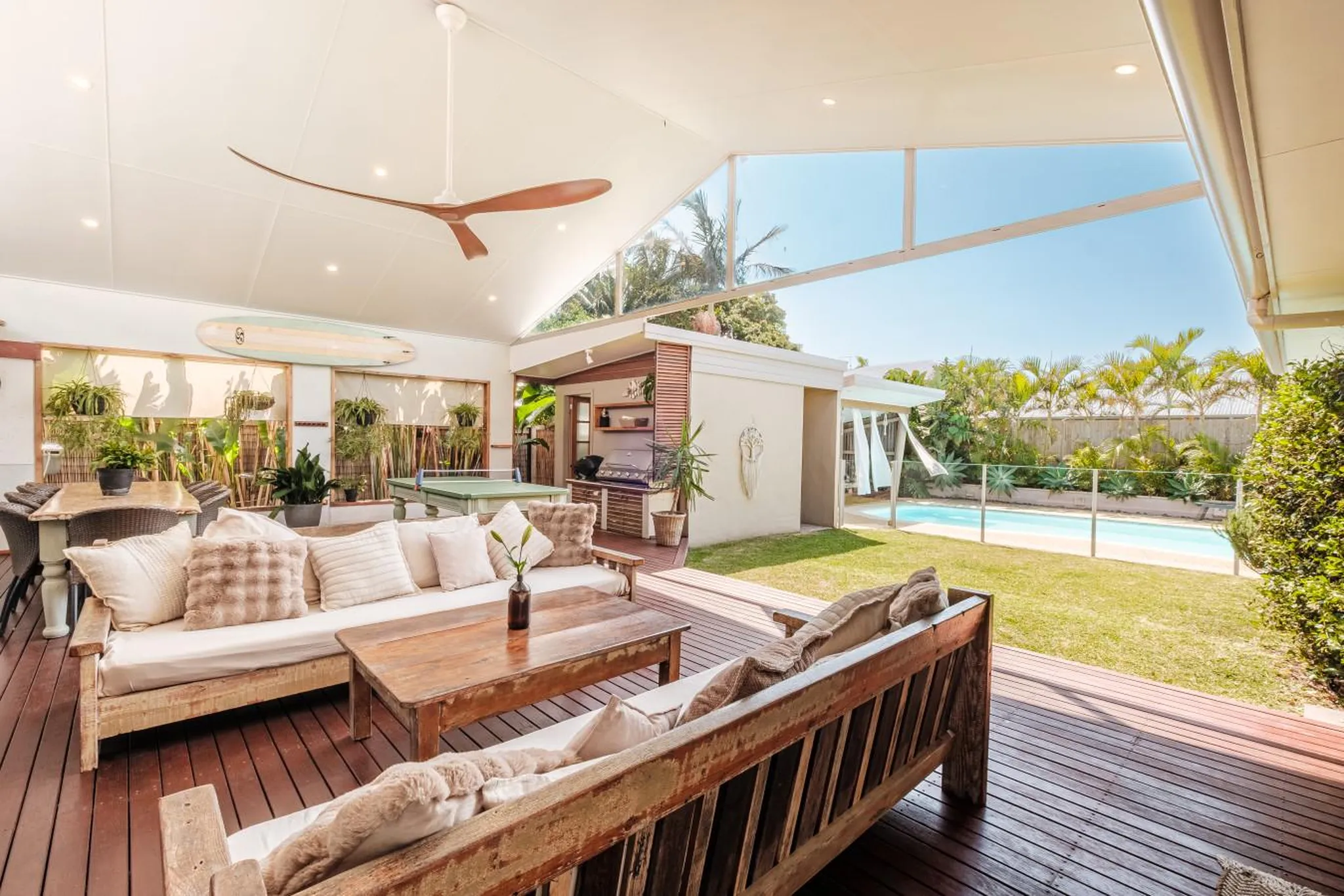 Outdoor patio with sofas, coffee table, and a pool in the background.