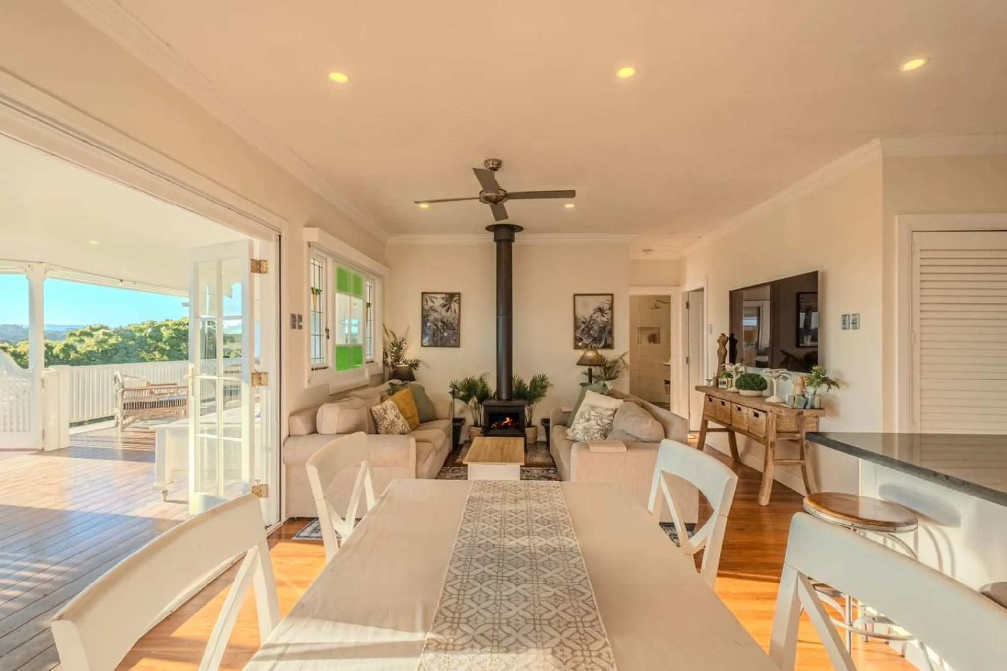 Living room with fireplace, two sofas, a dining table with chairs, and a TV mounted on the wall.