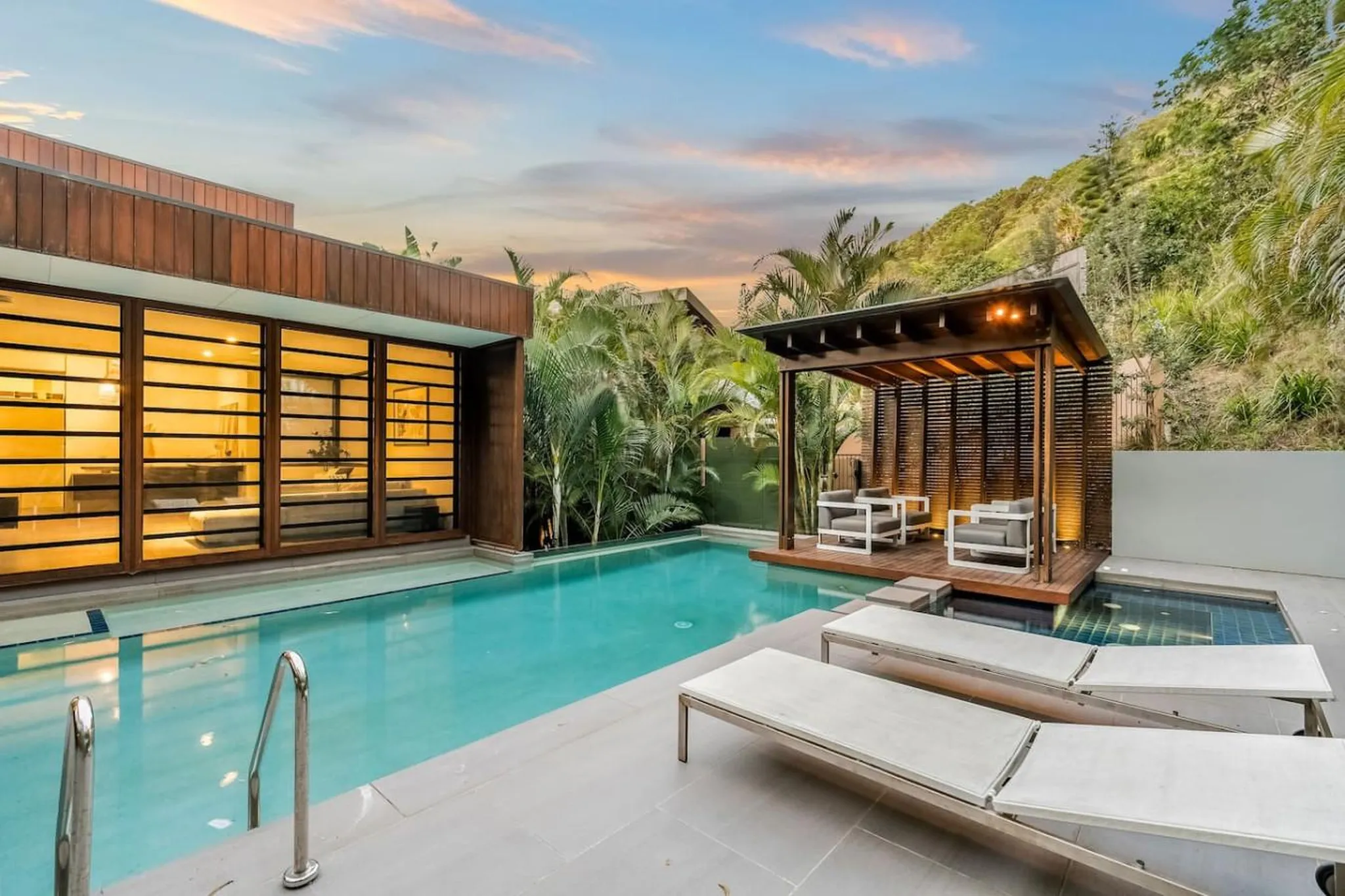 Luxury modern backyard with swimming pool, lounge chairs, and shaded outdoor seating.