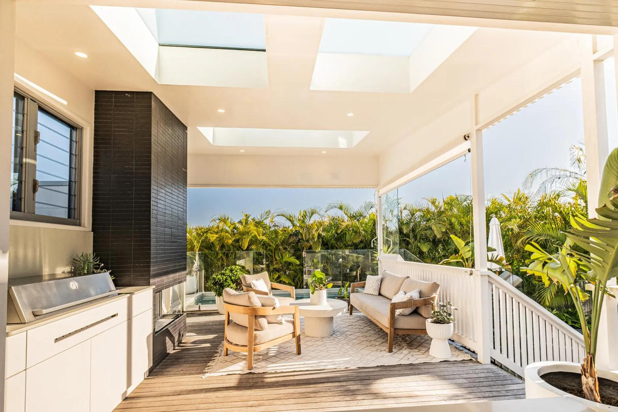 An outdoor living space with a grill, fireplace, and seating area overlooking lush greenery.