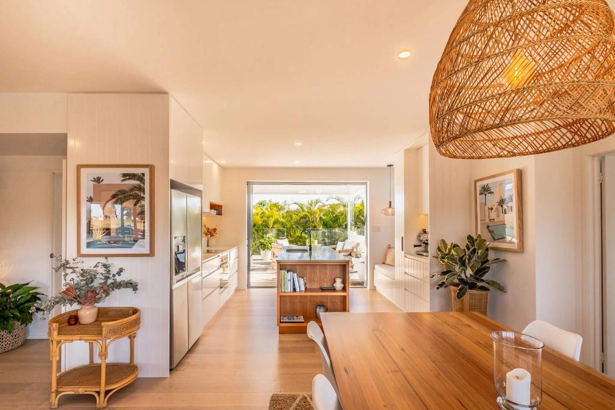 A modern kitchen and dining area with large sliding glass doors opening to a lush green outdoor spac