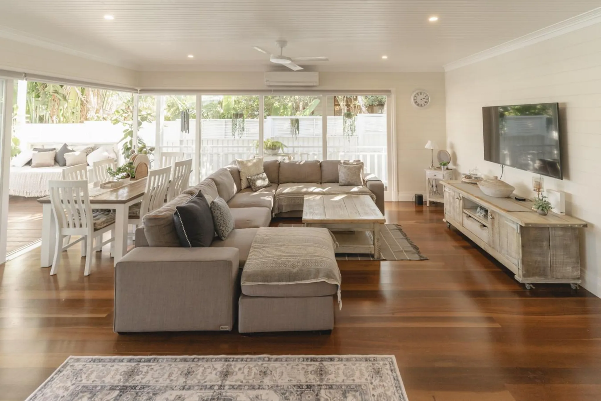 A sectional sofa, coffee table, and dining area are in a sunlit living room.