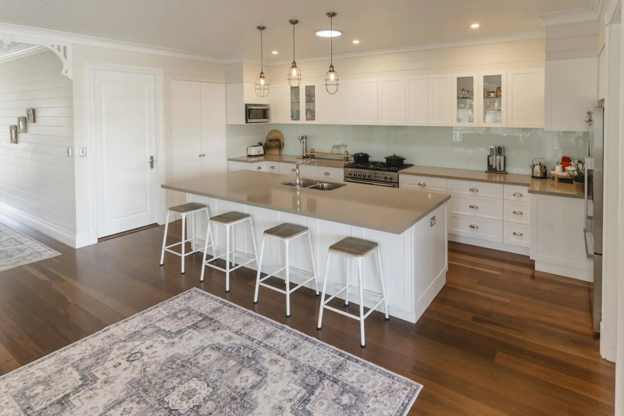 A white kitchen with a large island, a stovetop, and a sink.