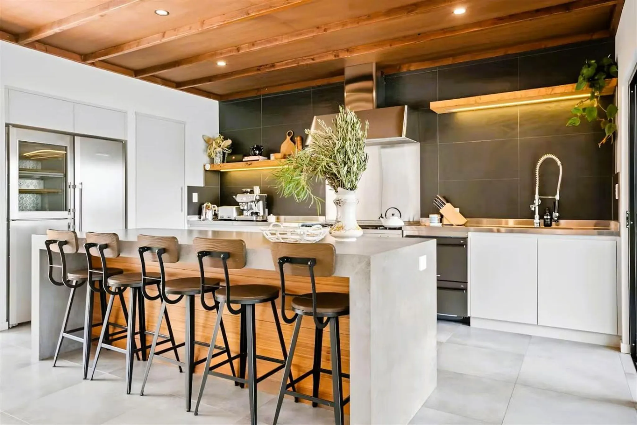 A modern kitchen with a concrete island and bar stools.