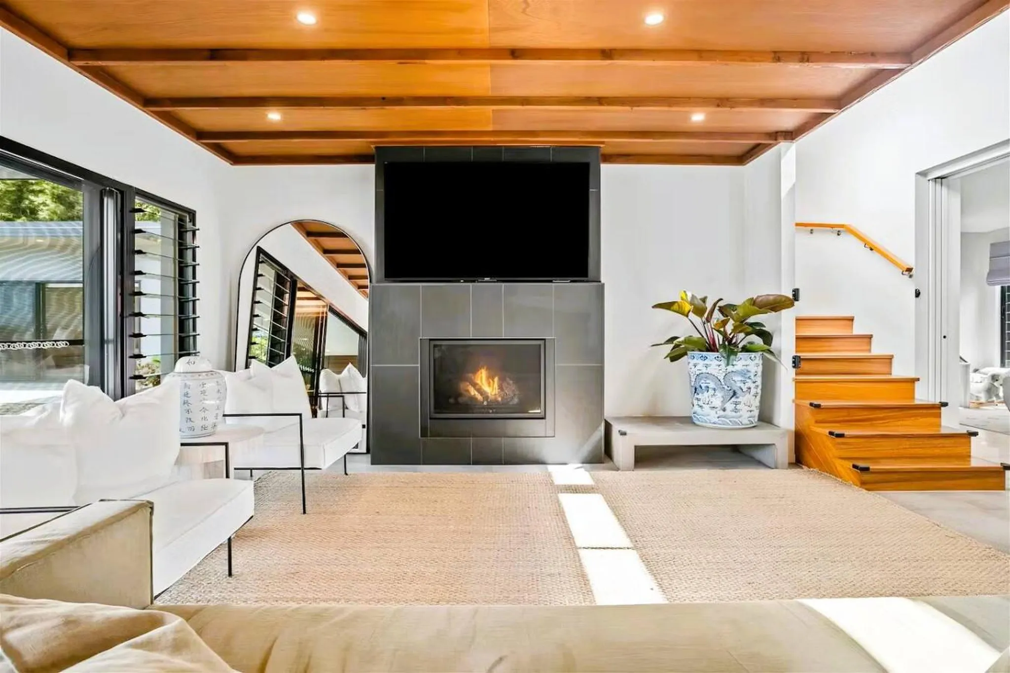 Modern living room with fireplace, TV, and wood ceiling.