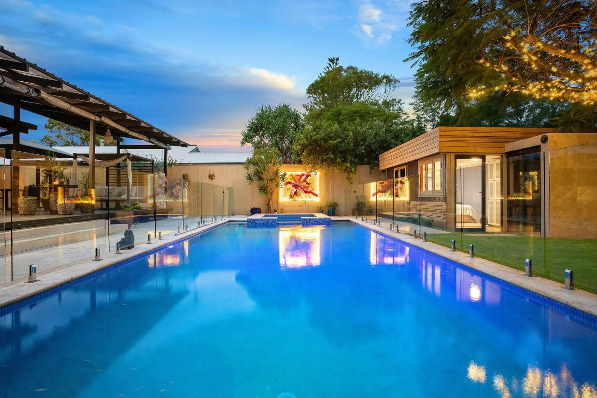 A luxurious backyard pool at dusk with modern architecture and ambient lighting.