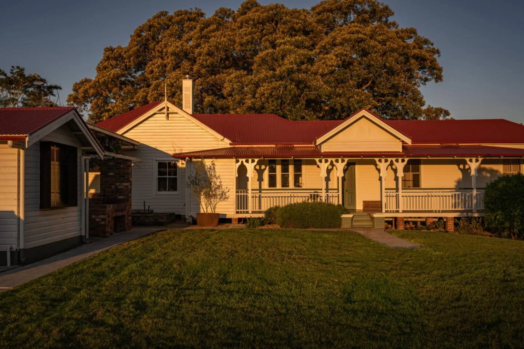 A traditional white house with a red roof, bathed in warm sunlight.