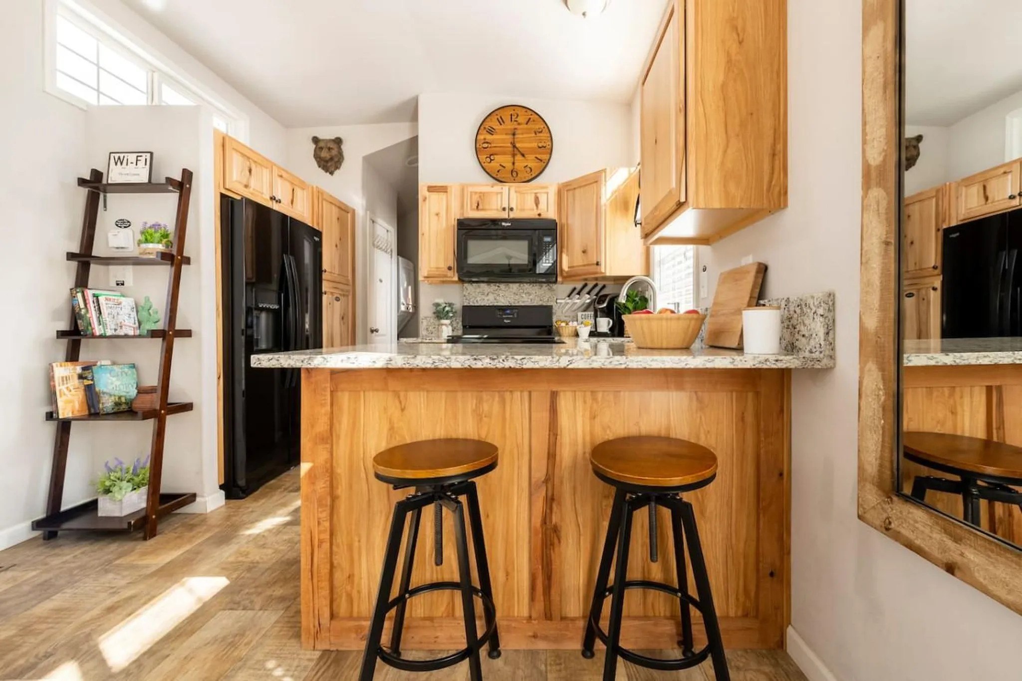 Kitchen with wooden cabinets, a black refrigerator, and a breakfast bar with stools.