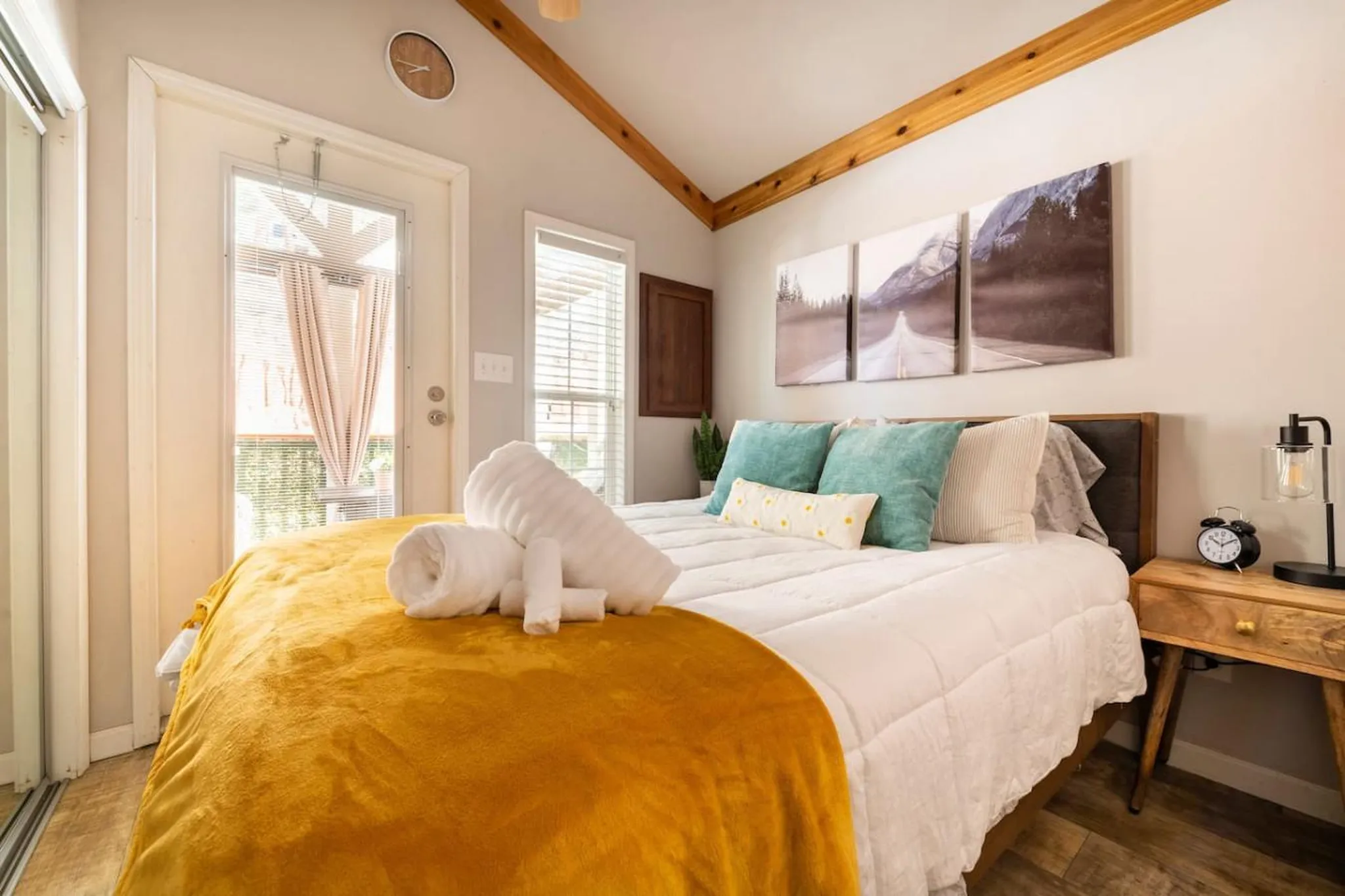 Bedroom with a bed, yellow blanket, and artwork.
