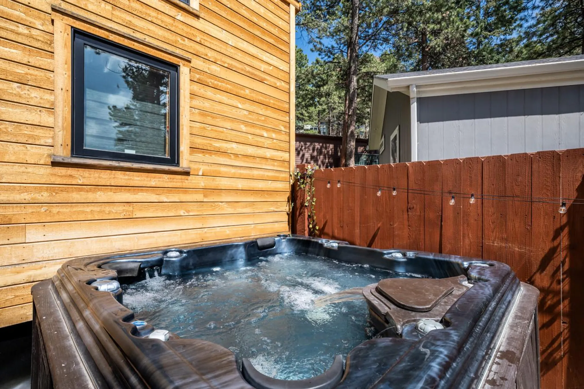 Outdoor hot tub with bubbling water next to a wooden-sided building.