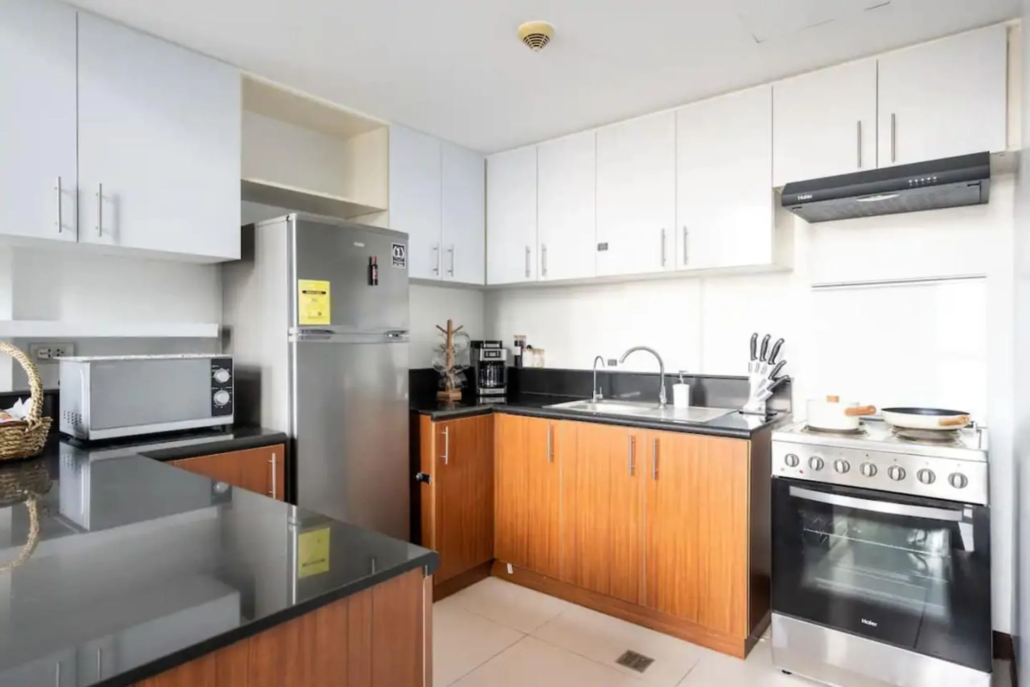 A modern kitchen with stainless steel appliances, white cabinets, and wood-look lower cabinets.