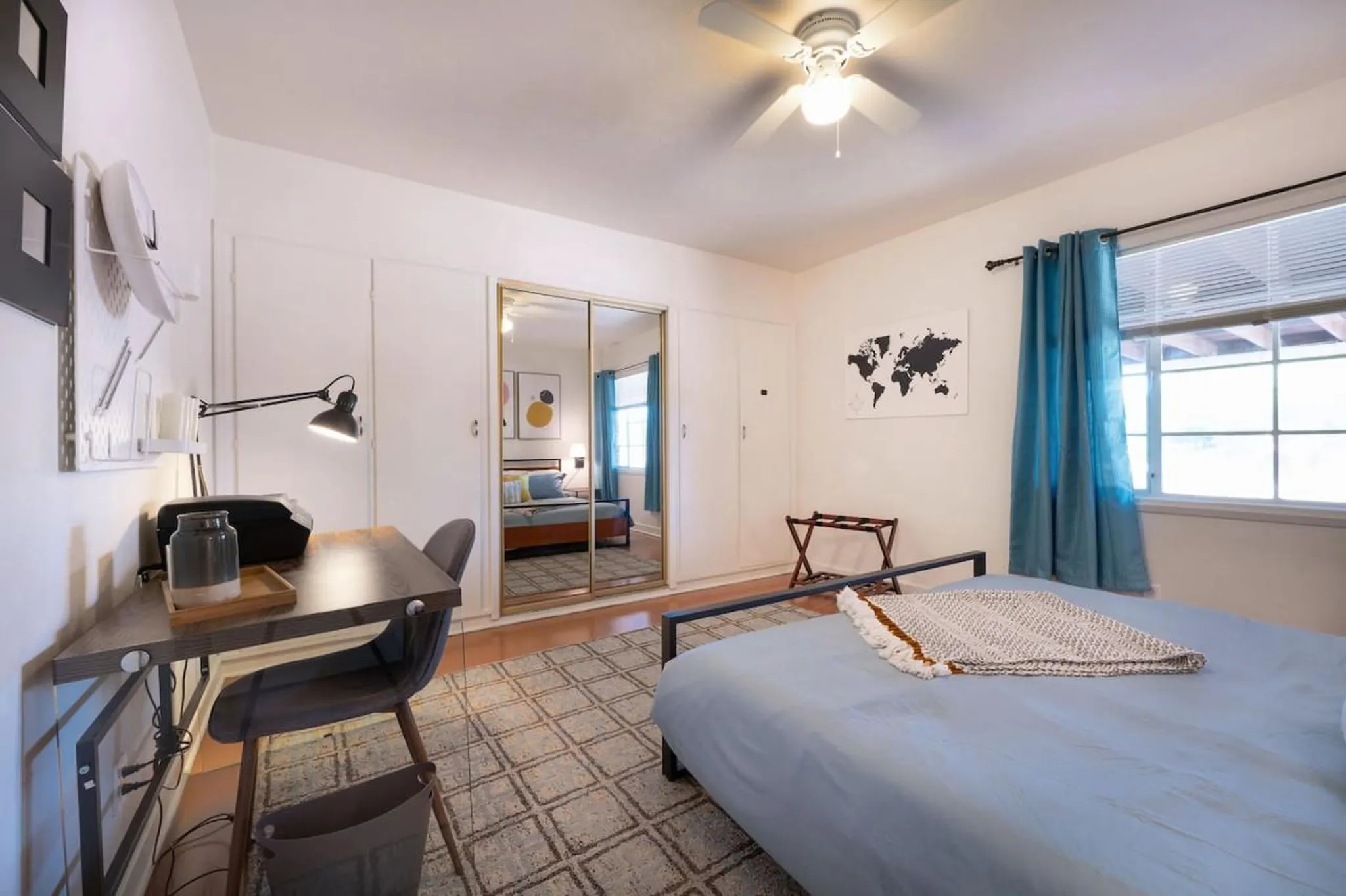 A bedroom with a desk, bed, and mirrored closet.