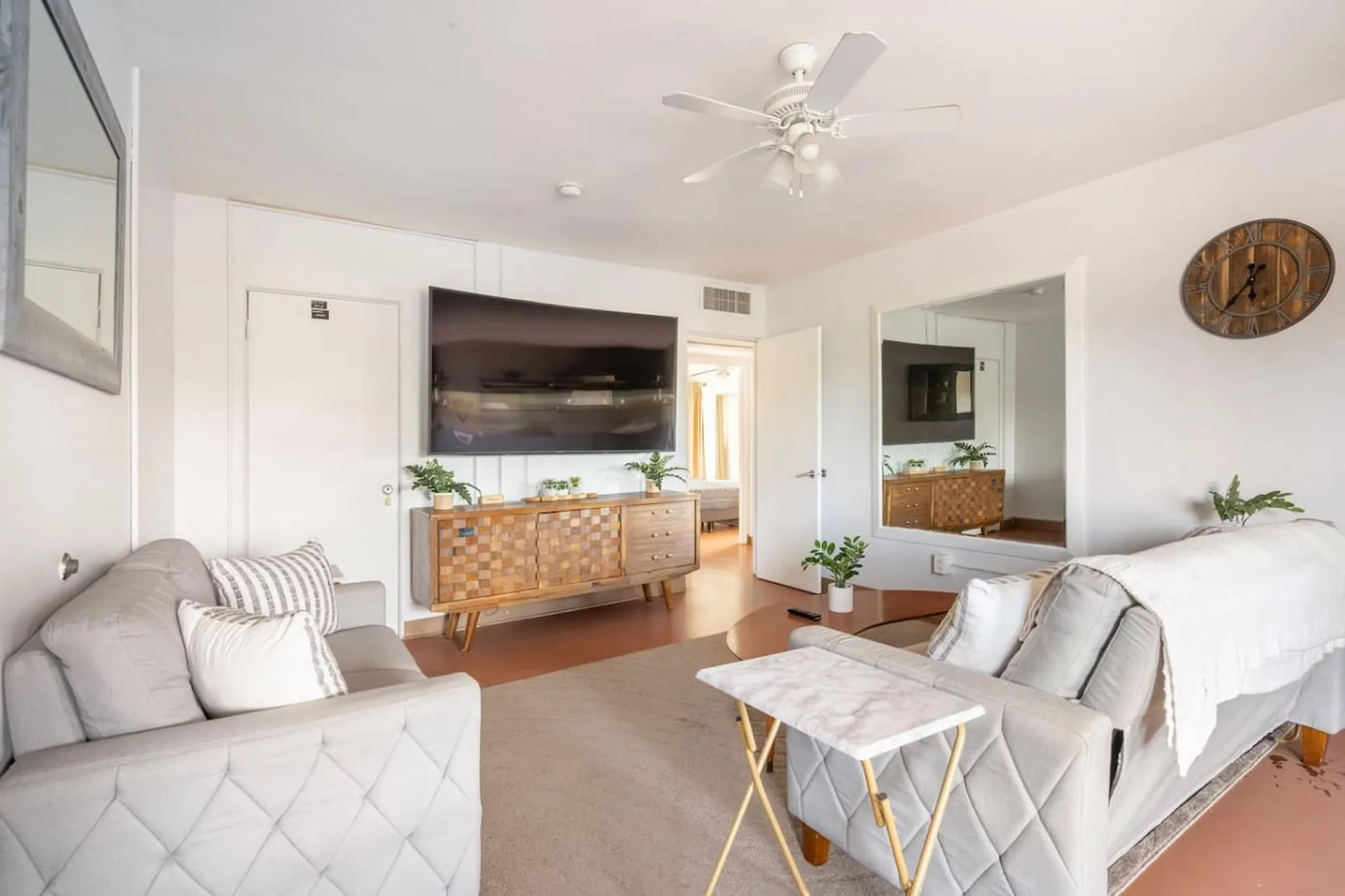 A living room with a TV, sofa, credenza, and a ceiling fan.