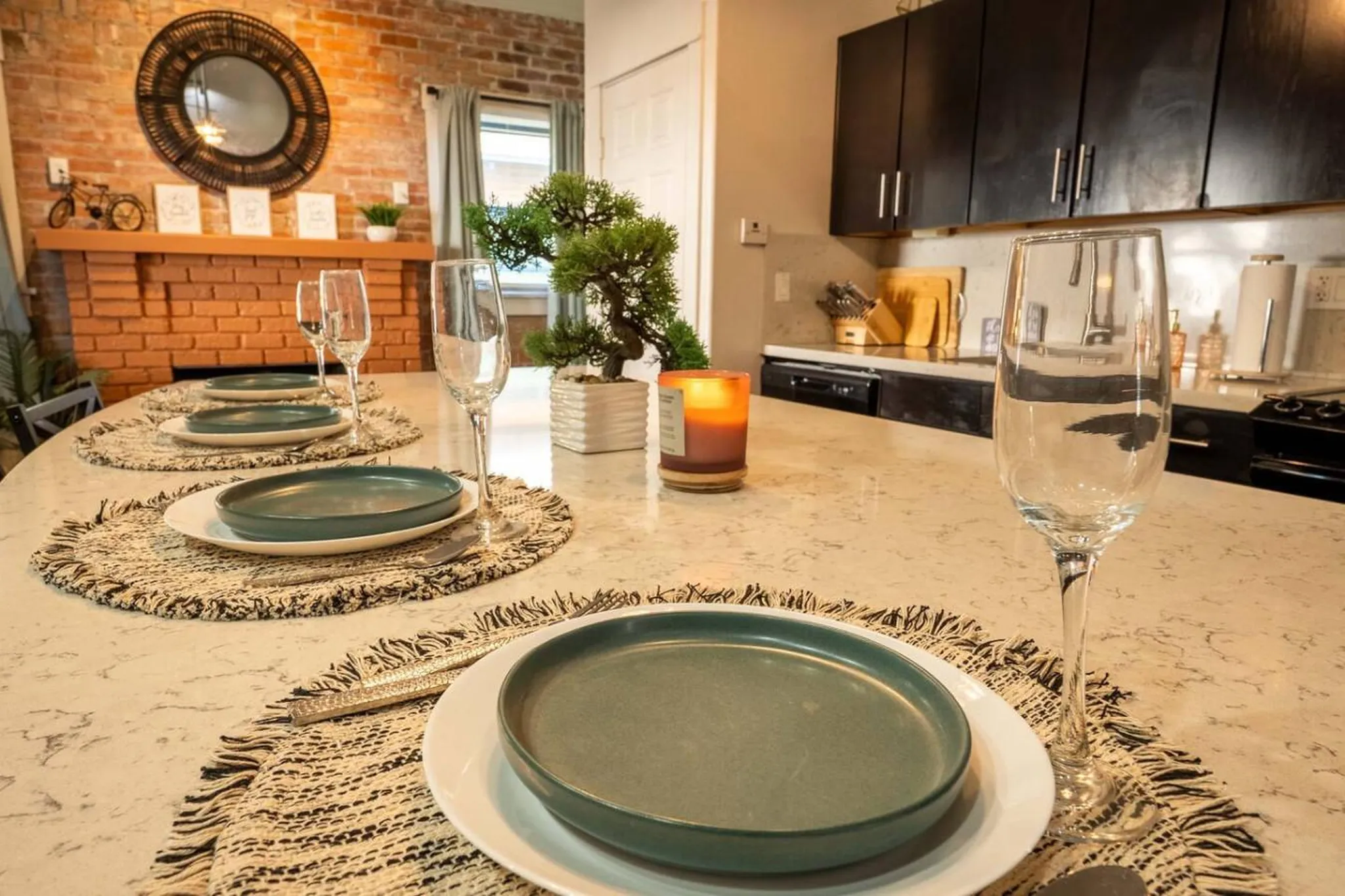 A dining table is set with plates, glasses, and a candle.