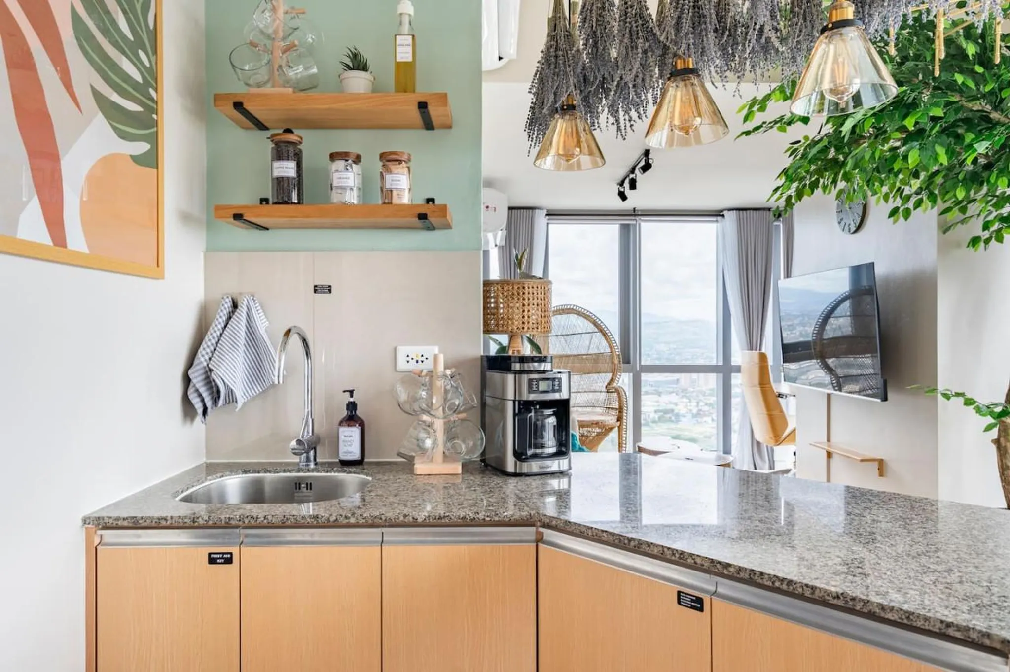 A kitchen with a sink, coffee maker, and hanging mugs.