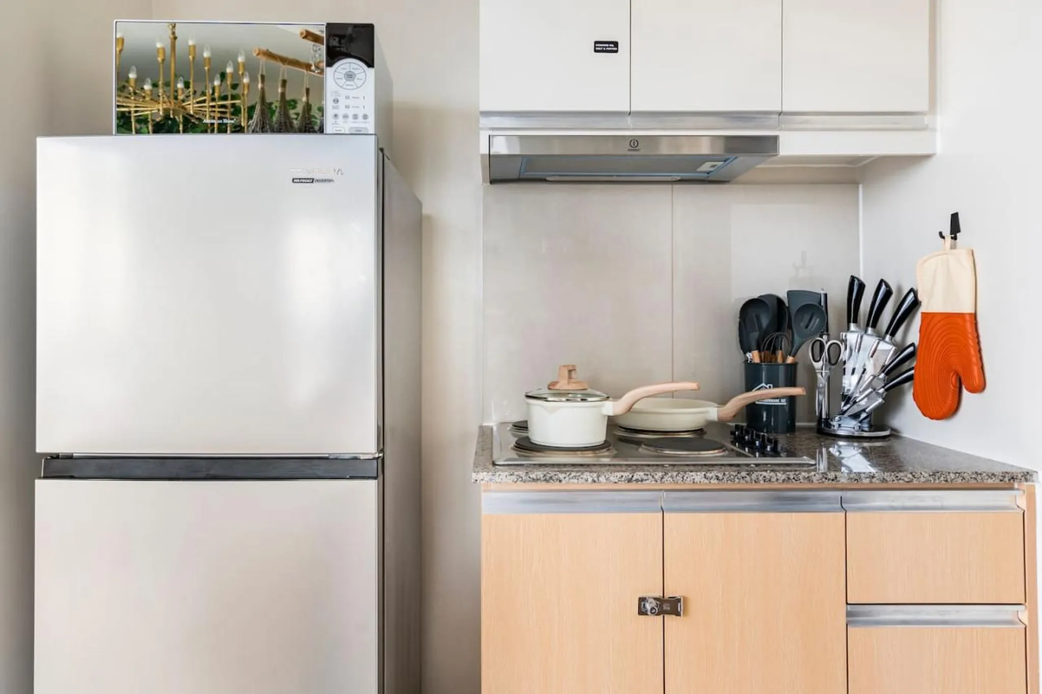 A stainless steel refrigerator is next to a stove with cooking utensils.
