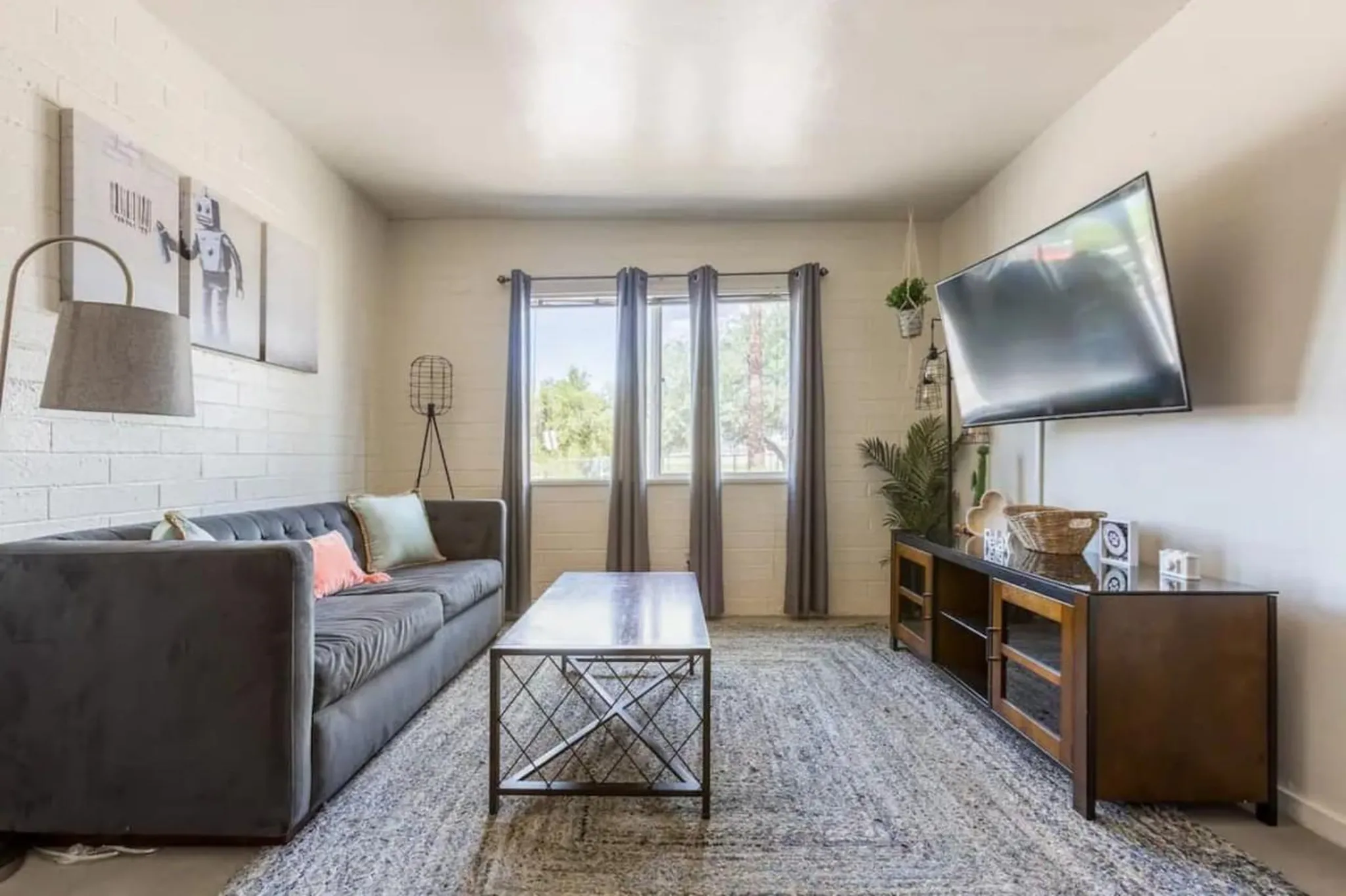 Living room with grey sofa, metal coffee table, and television.