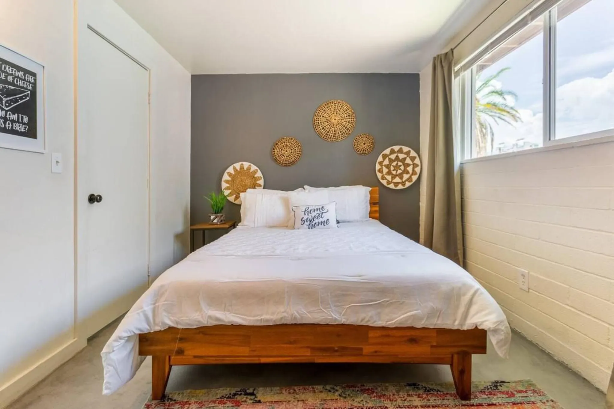 A white bed with white pillows sits against a grey wall.