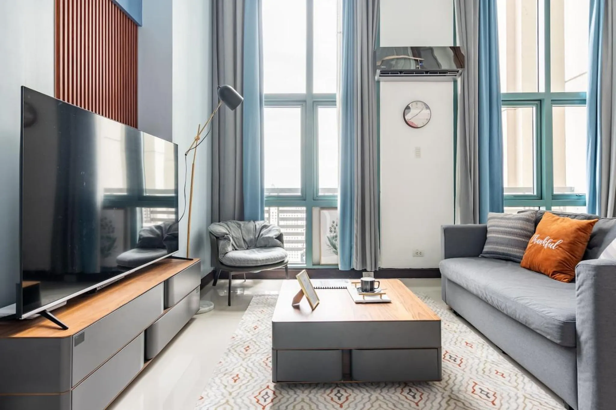 A modern living room with a grey sofa, coffee table, and TV.