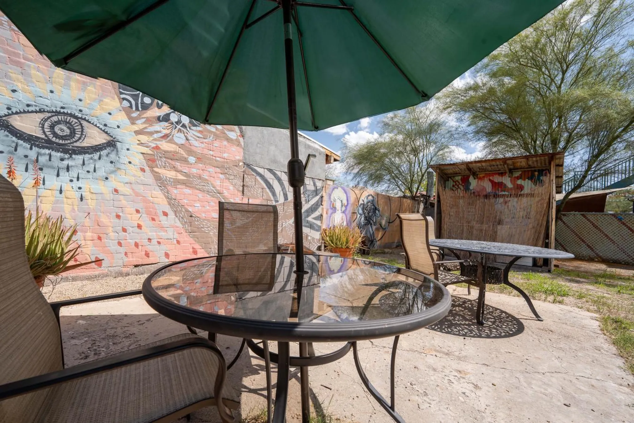 An outdoor patio with a table and chairs in front of a colorful mural.