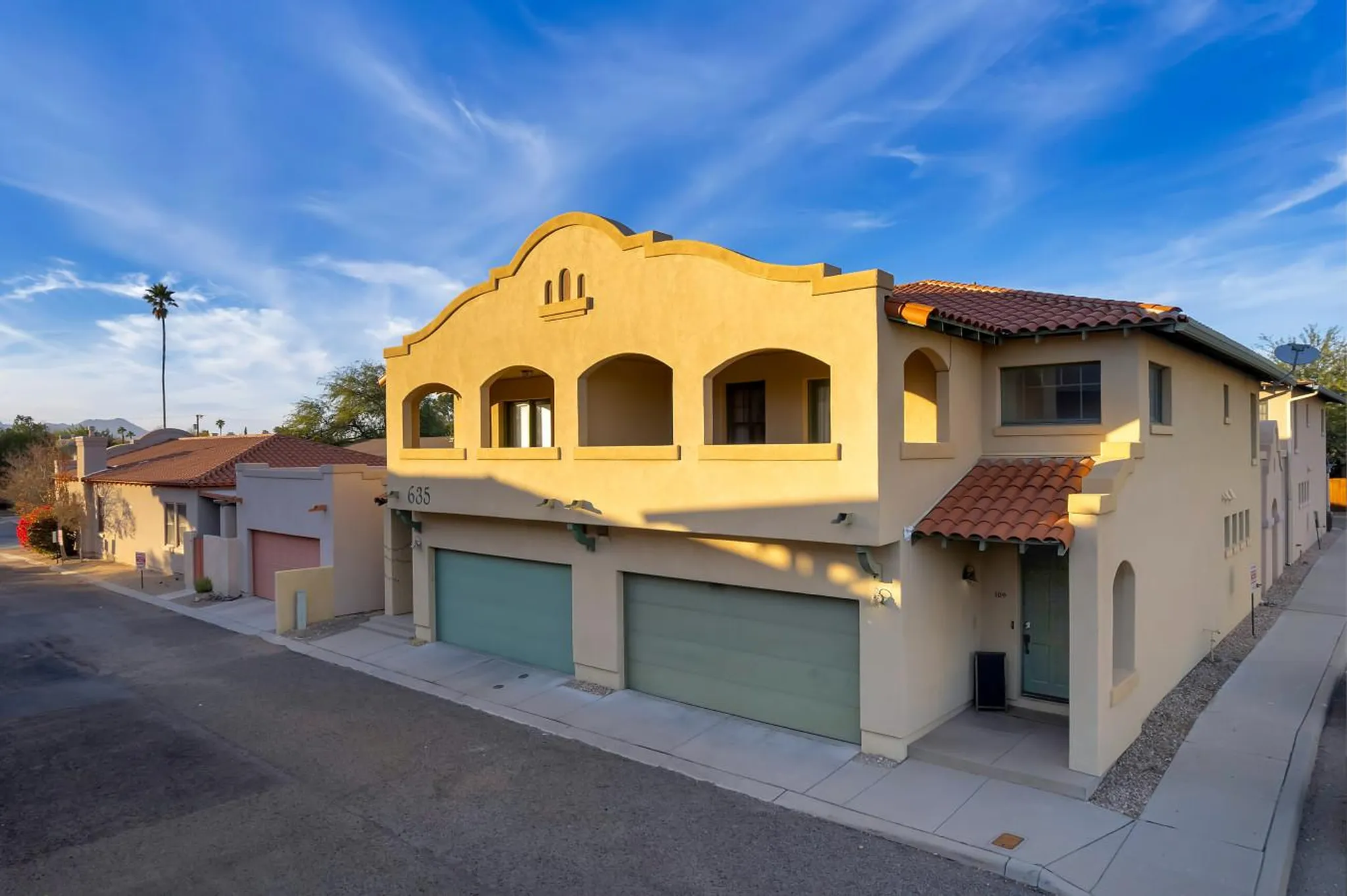 A stucco building with a red tile roof and arched windows.