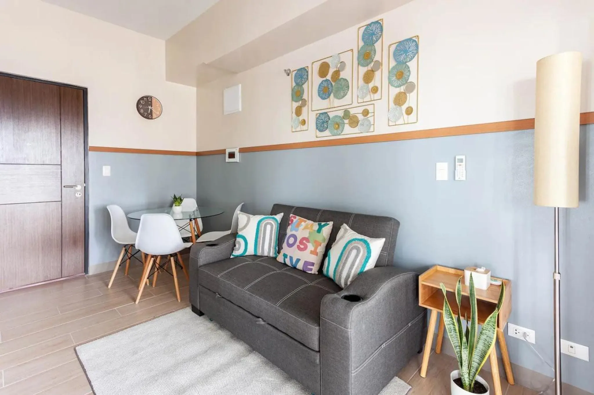 A sofa with decorative pillows is in front of a wall with art.