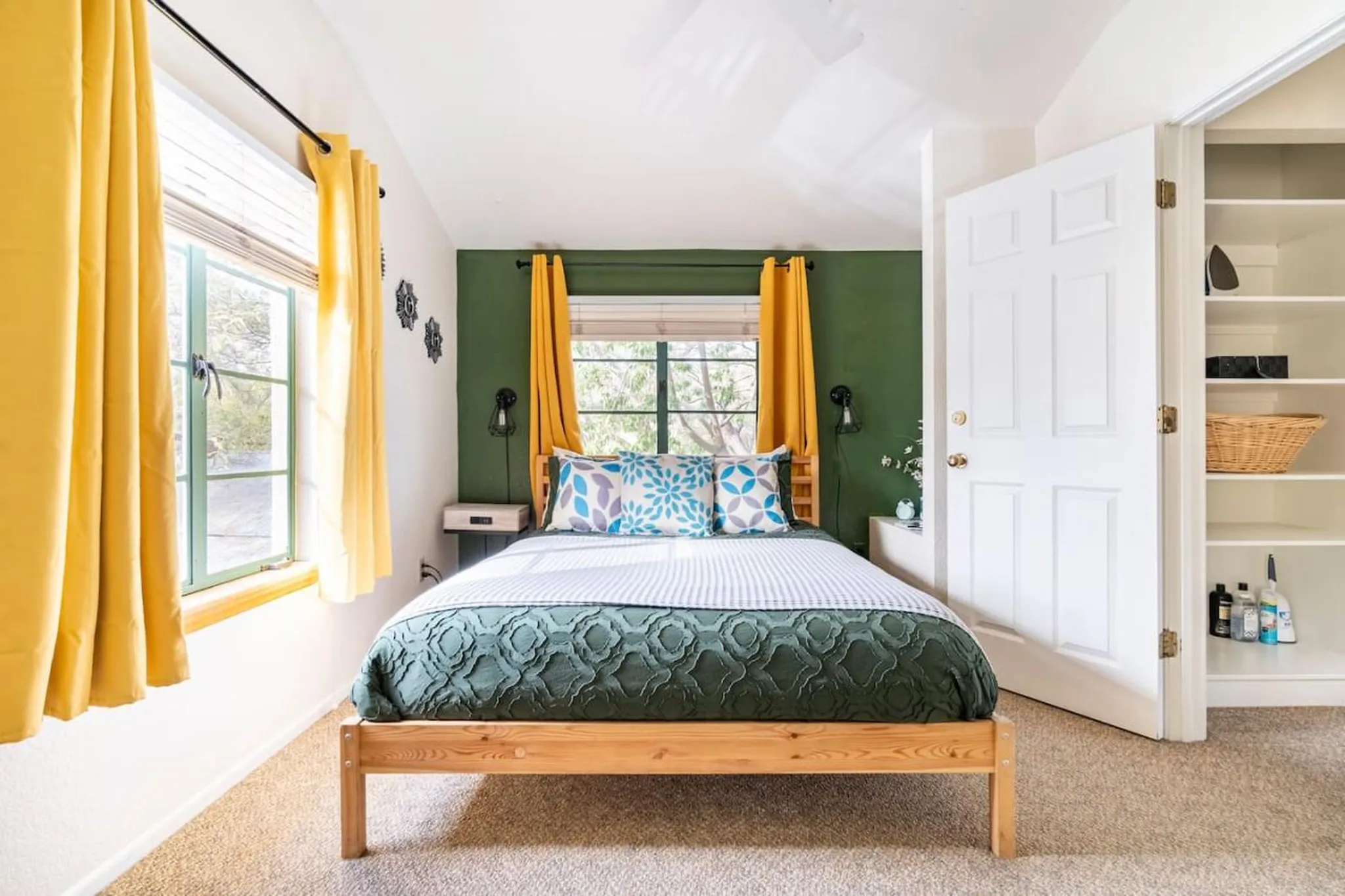 A cozy bedroom with a wood-frame bed, green walls, and yellow curtains.