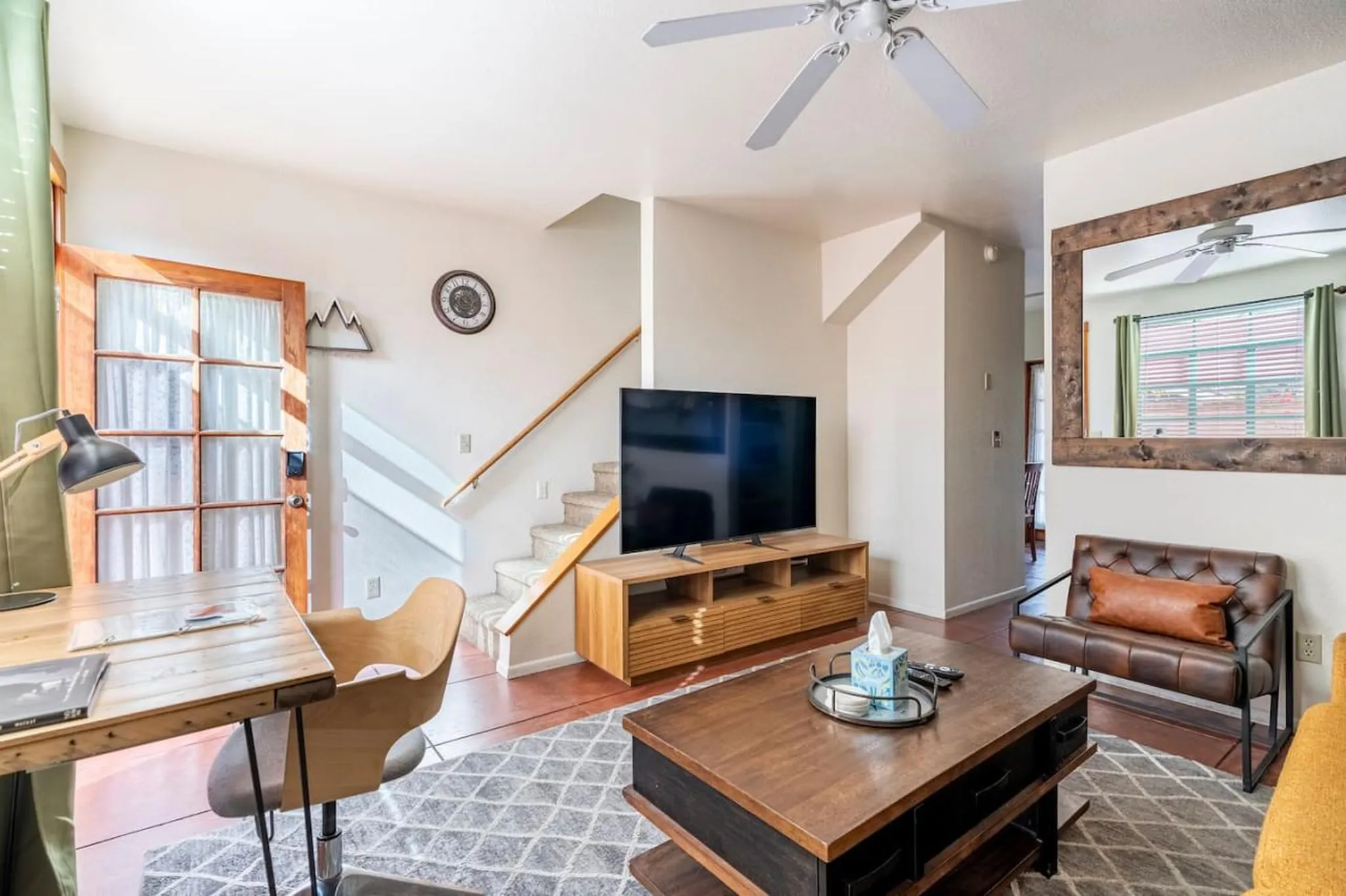 A cozy living room with a desk, TV, coffee table, and a stylish leather chair.