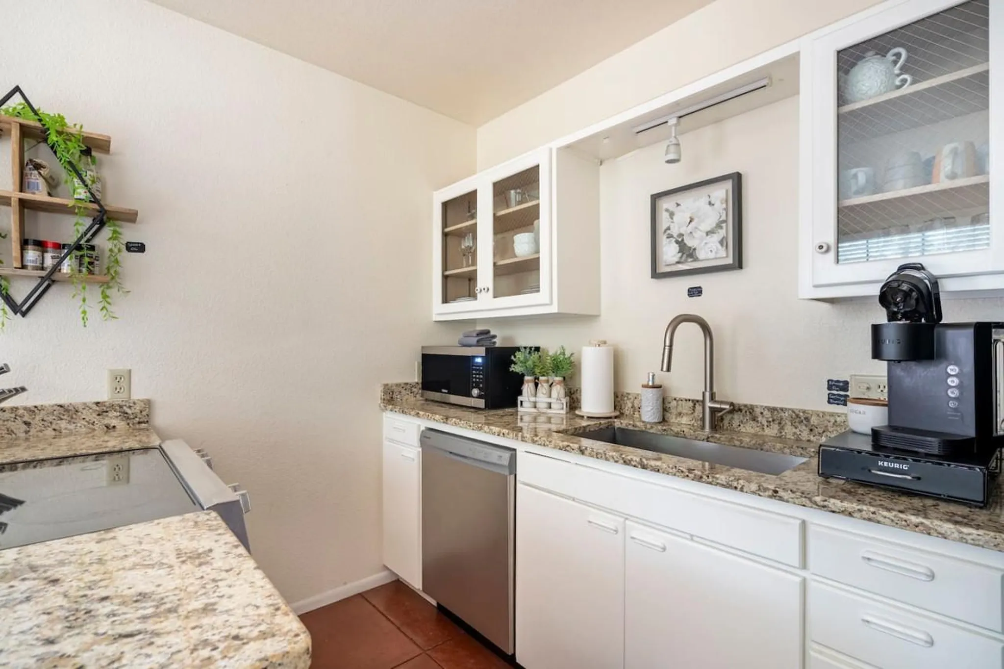 A white modern kitchen with granite countertops, appliances, and decor.