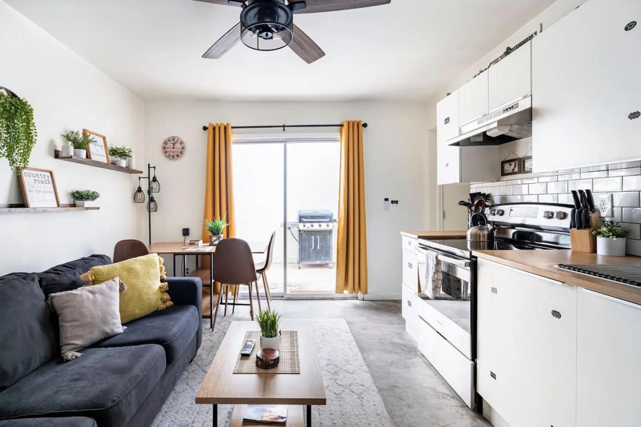 A modern studio apartment with a couch, dining area, and kitchen.