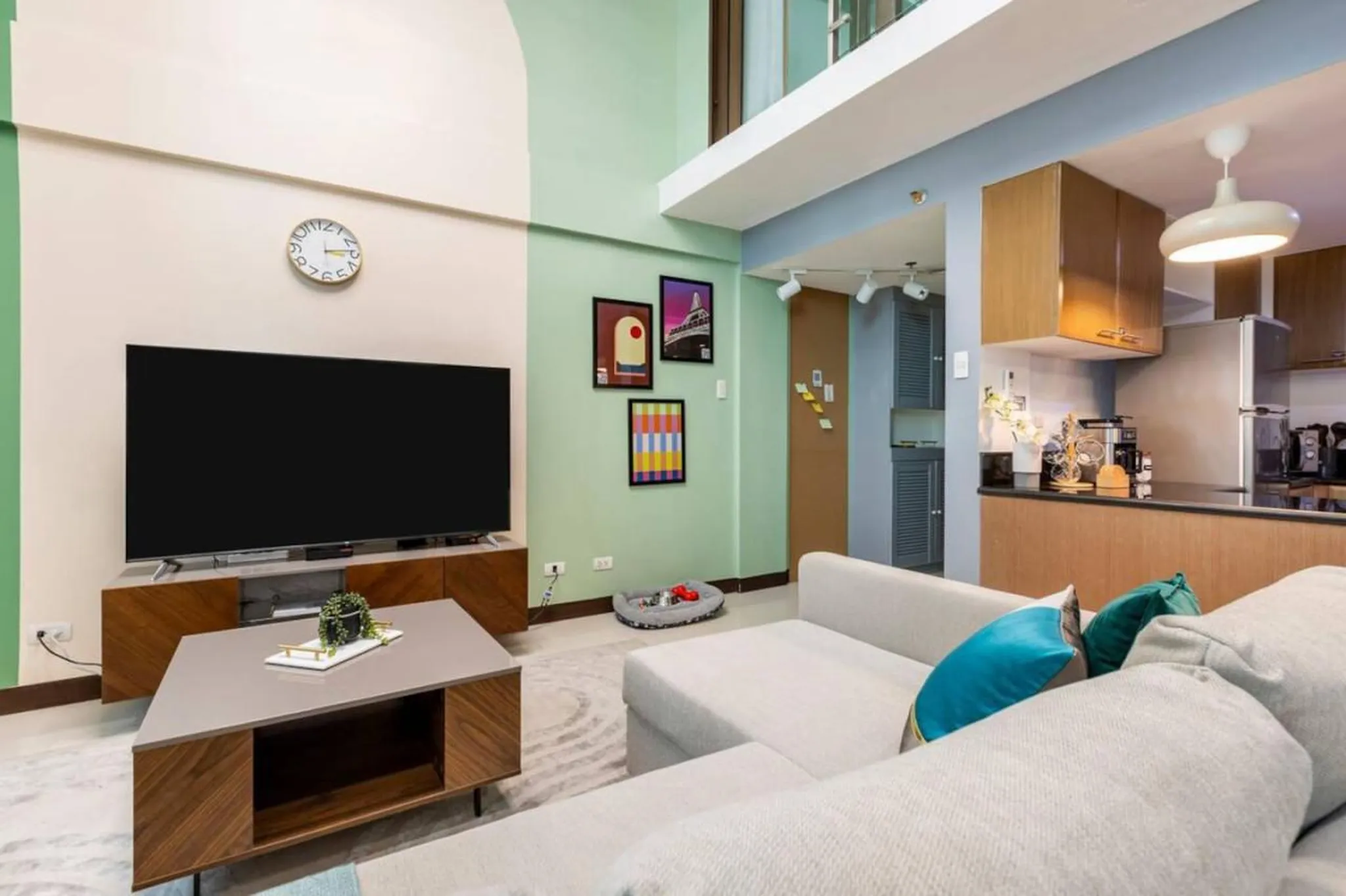 A living room with a sectional couch, TV, coffee table, and kitchen area.