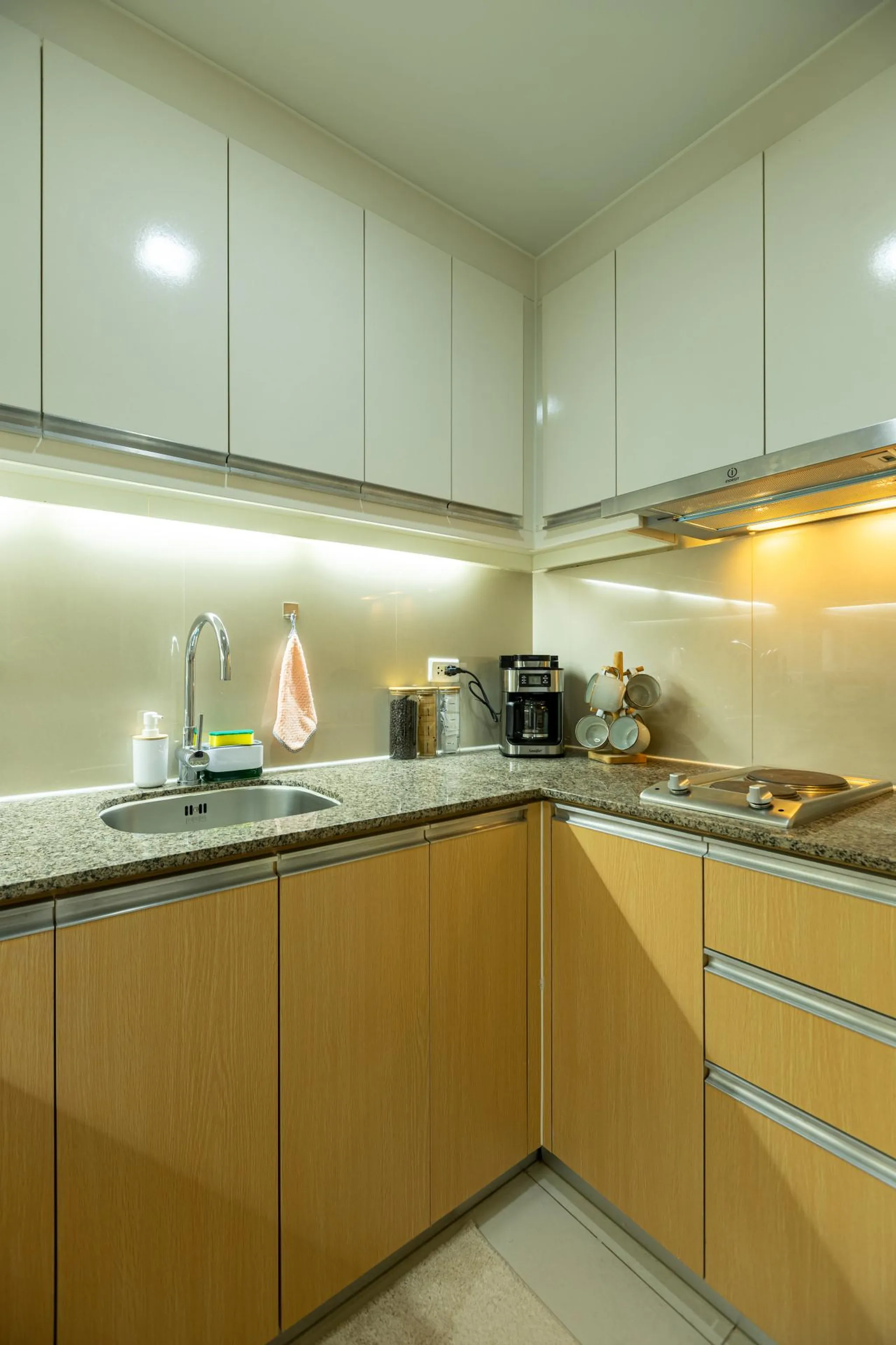 A modern corner kitchen with white cabinets, granite countertops, and wood cabinets.