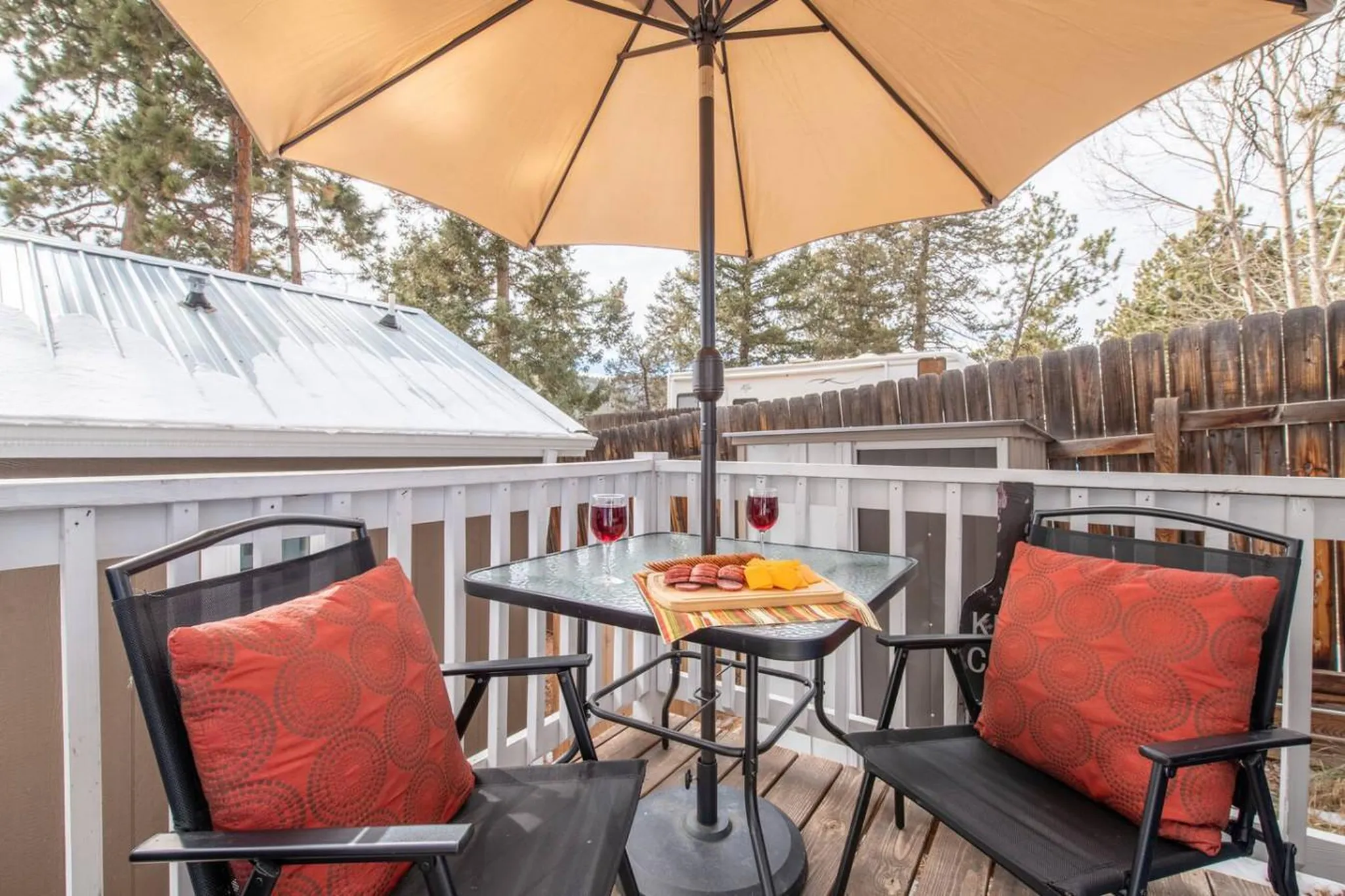 Outdoor patio with a table, two chairs, and a platter of meat and cheese.
