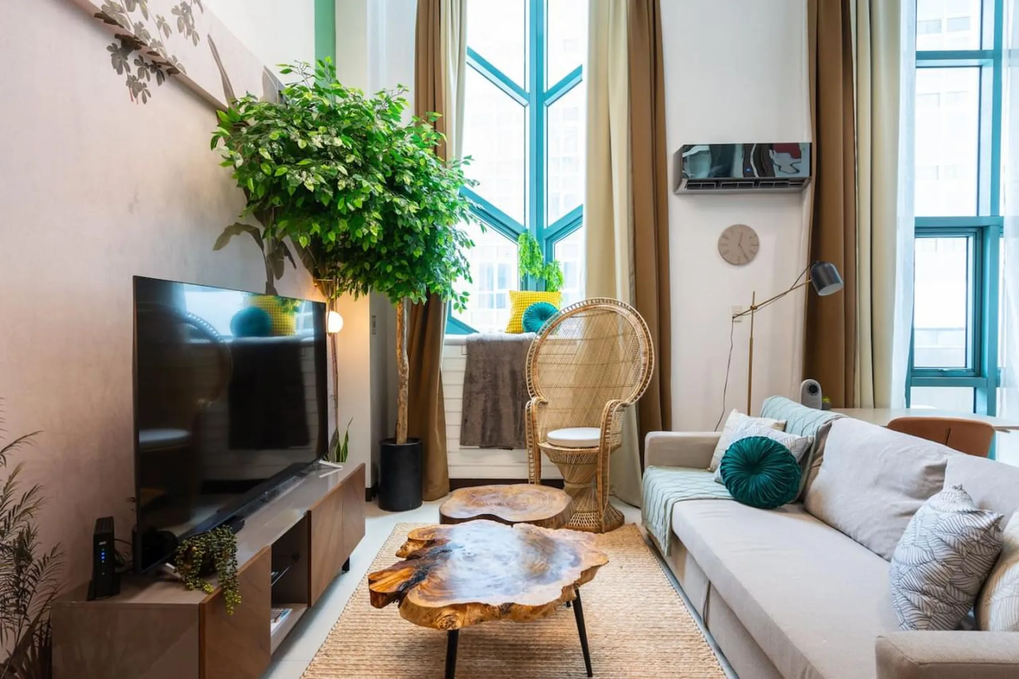 A modern living room with a TV, couch, coffee table, and decorative plant.