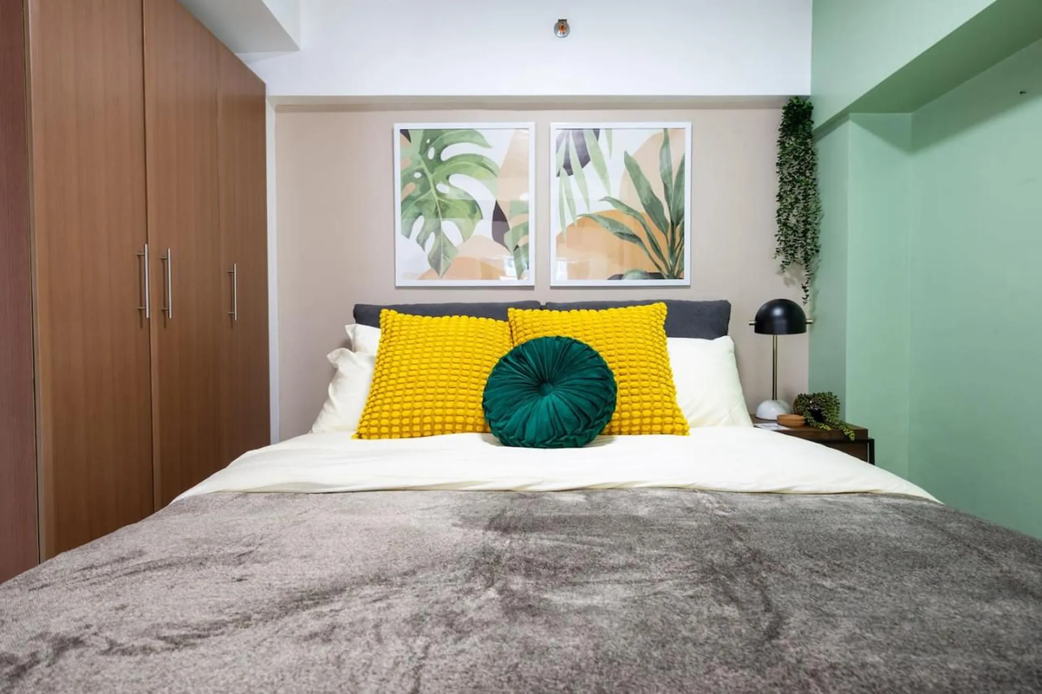 A bedroom with a bed, two yellow pillows, and a green round pillow.