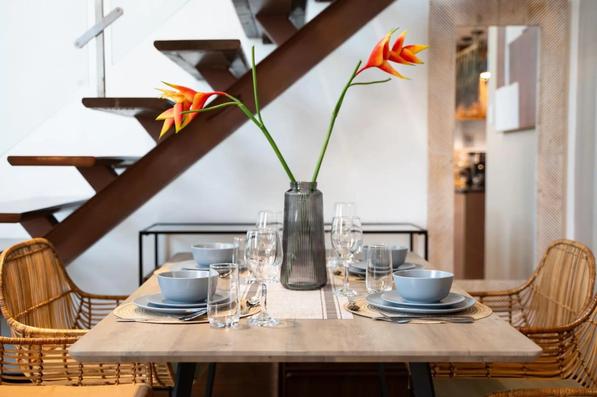 A dining table is set for a meal with blue bowls, plates, and silverware.