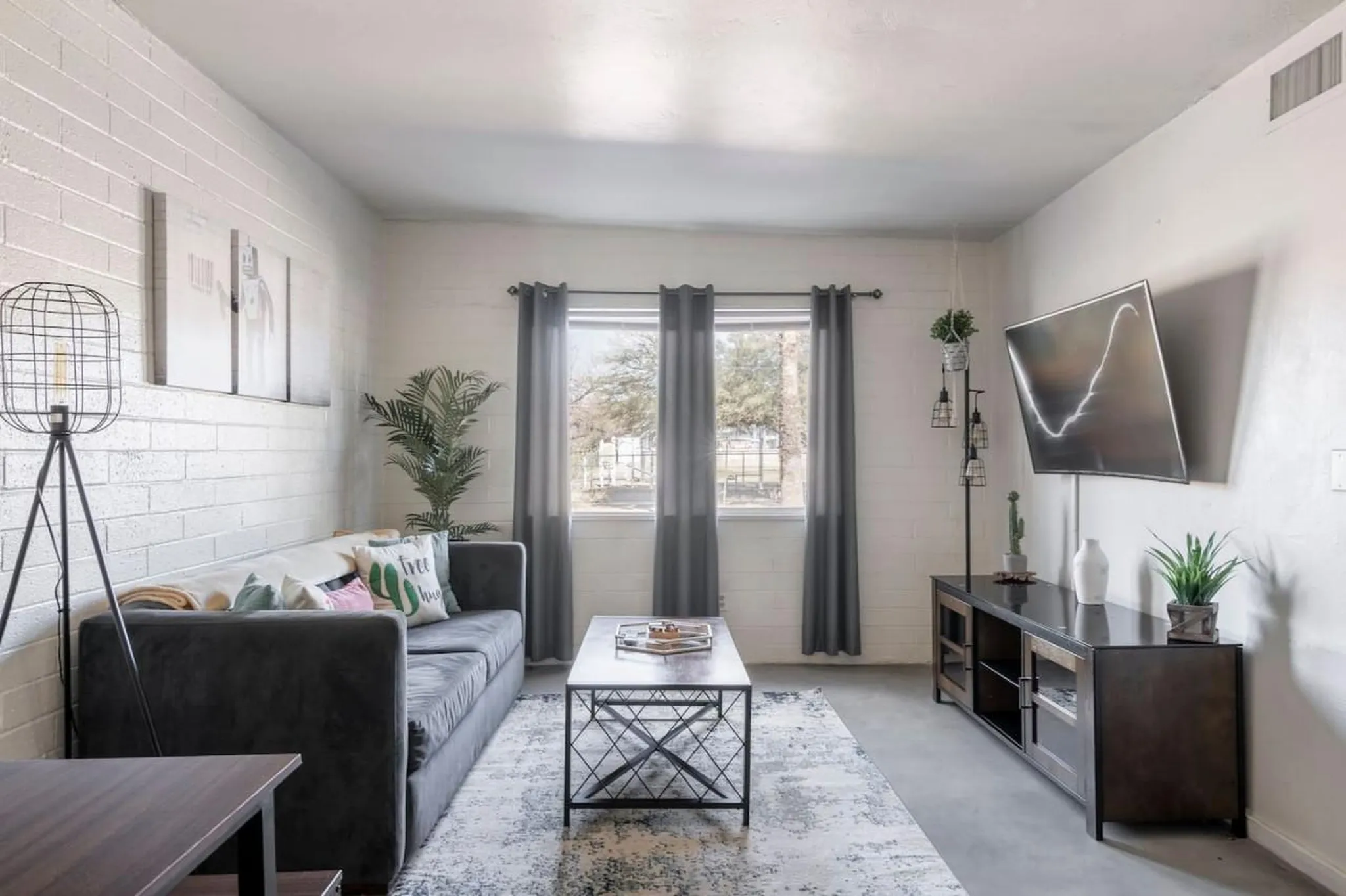 A living room with a couch, TV, coffee table, and floor lamp.