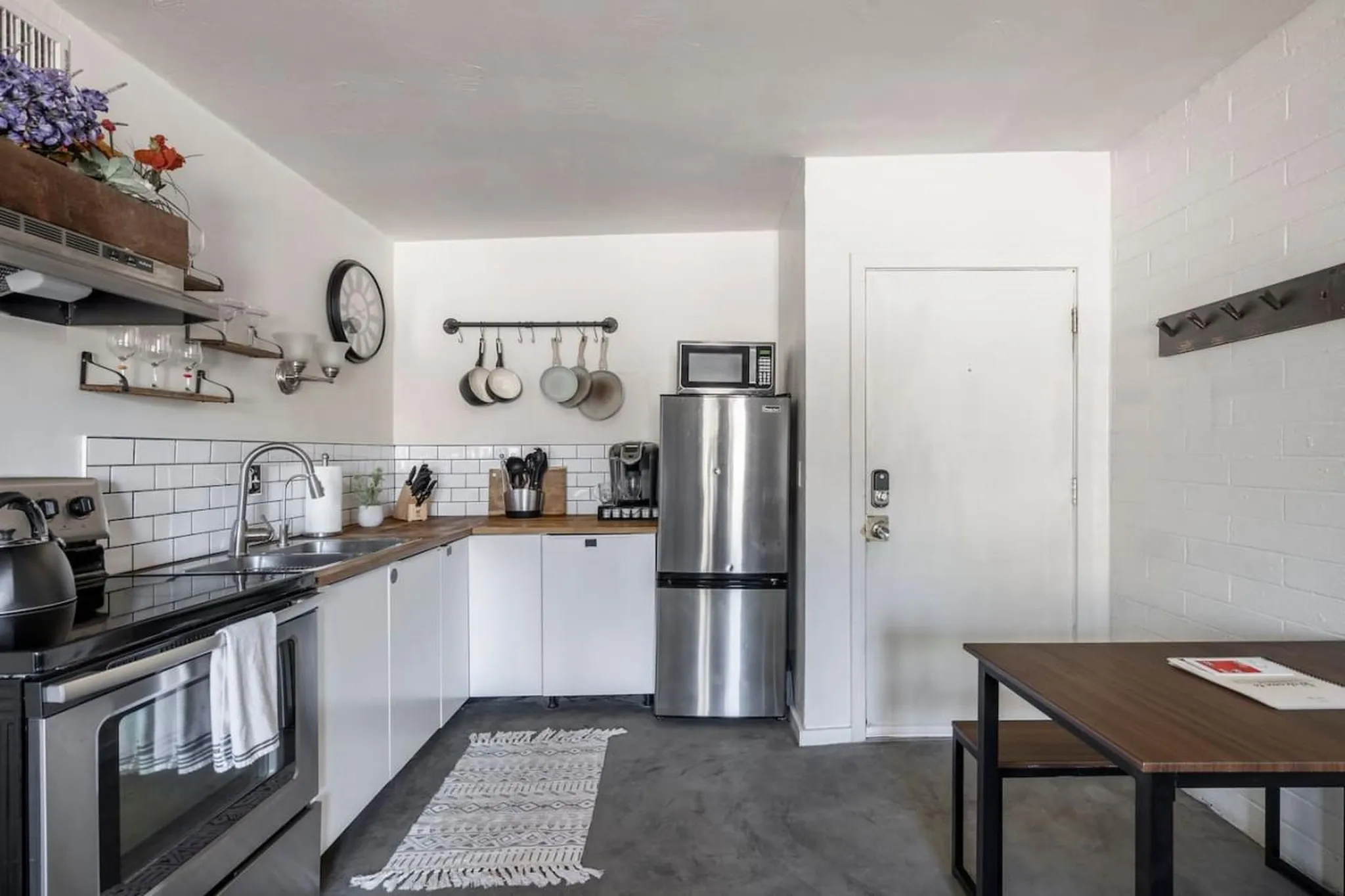 A modern kitchen with stainless steel appliances, white cabinets, and a wooden countertop.