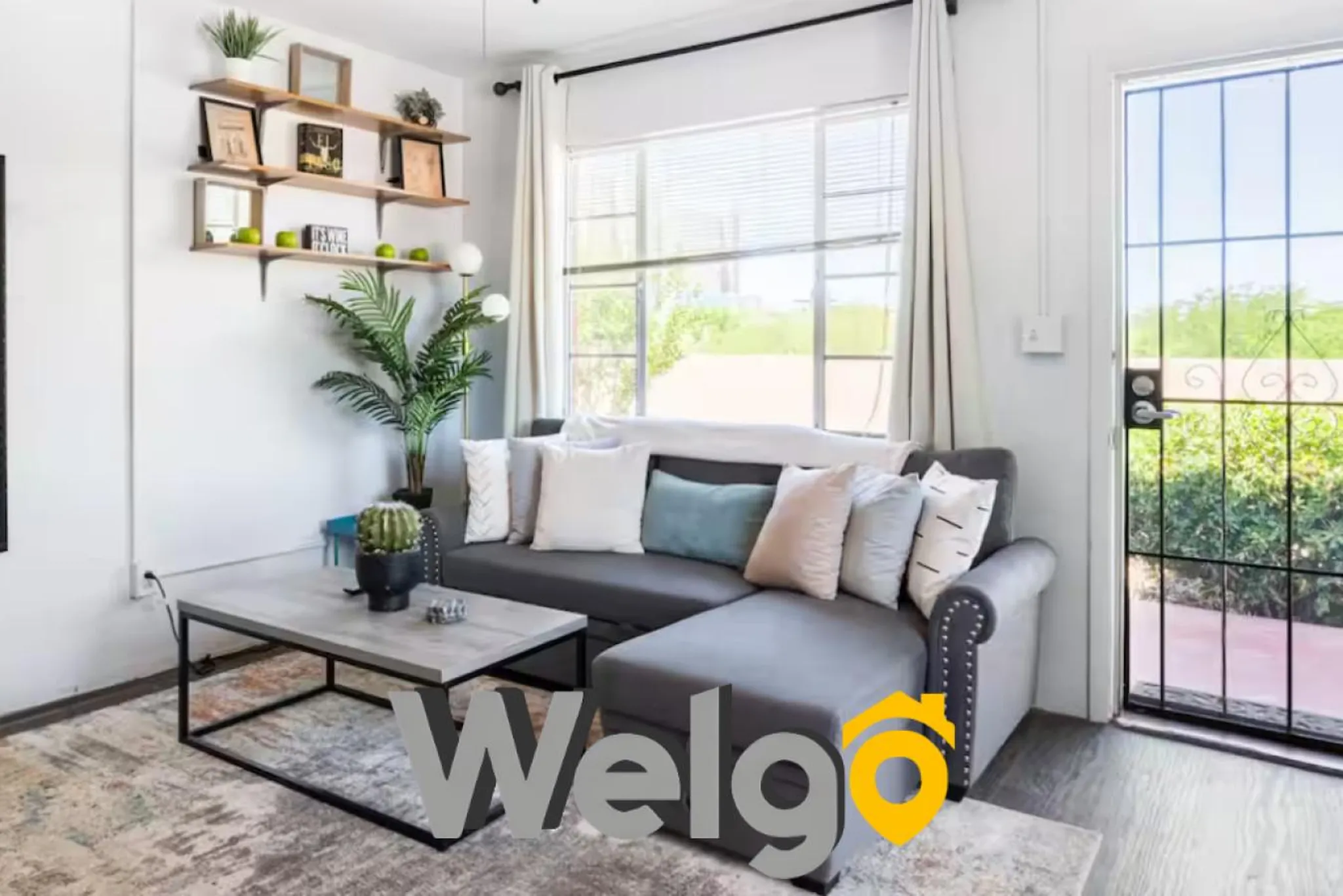 A living room with a gray sectional sofa, coffee table, and shelves filled with decor.