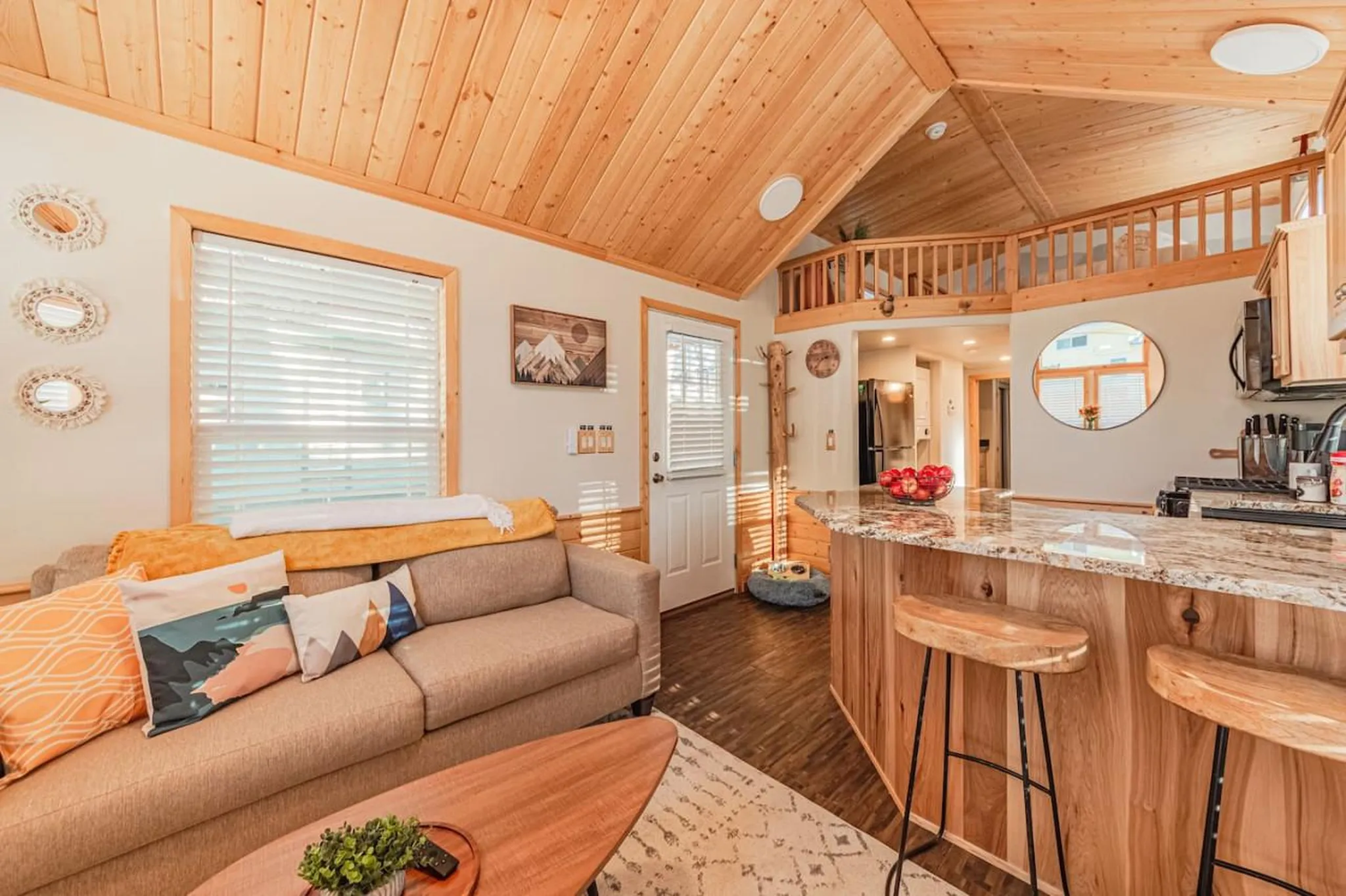 A cozy living room and kitchen area with wooden accents and a loft.