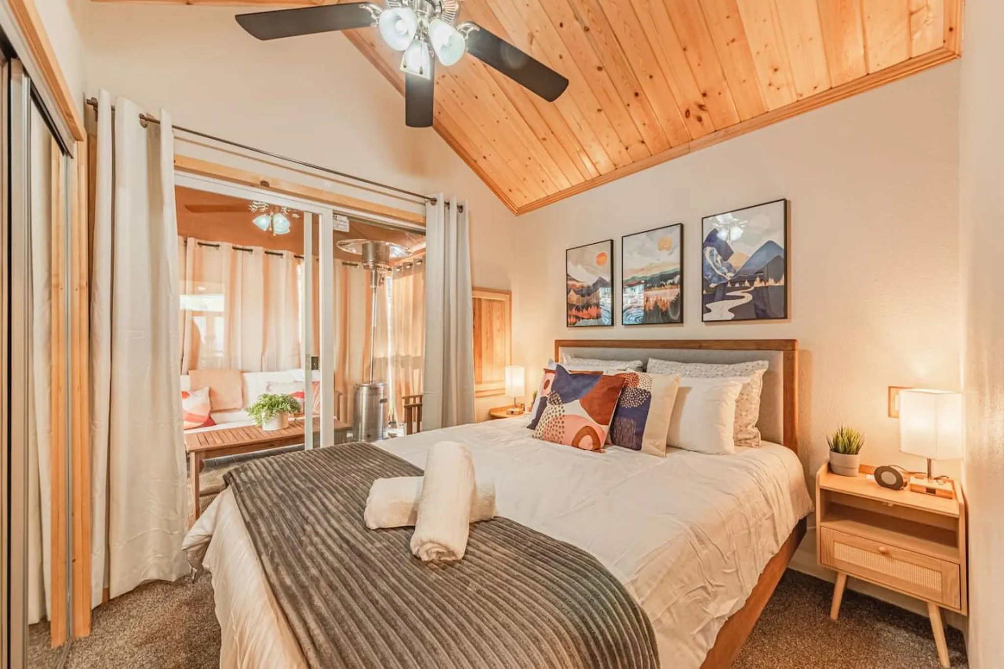 Cozy bedroom with a large bed, colorful pillows, and a view of an outdoor patio.