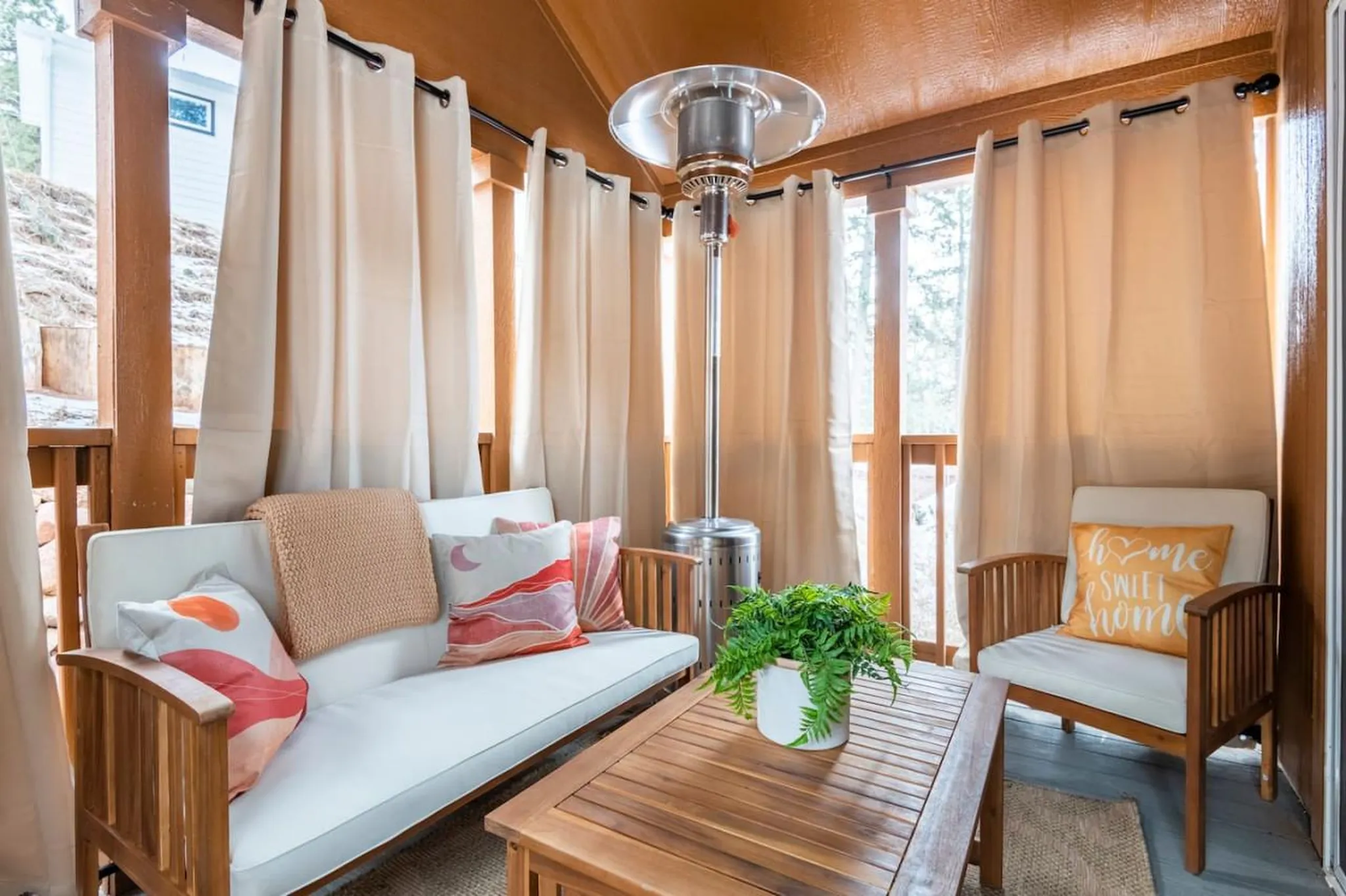 An outdoor seating area with a couch, chair, coffee table, and heater.