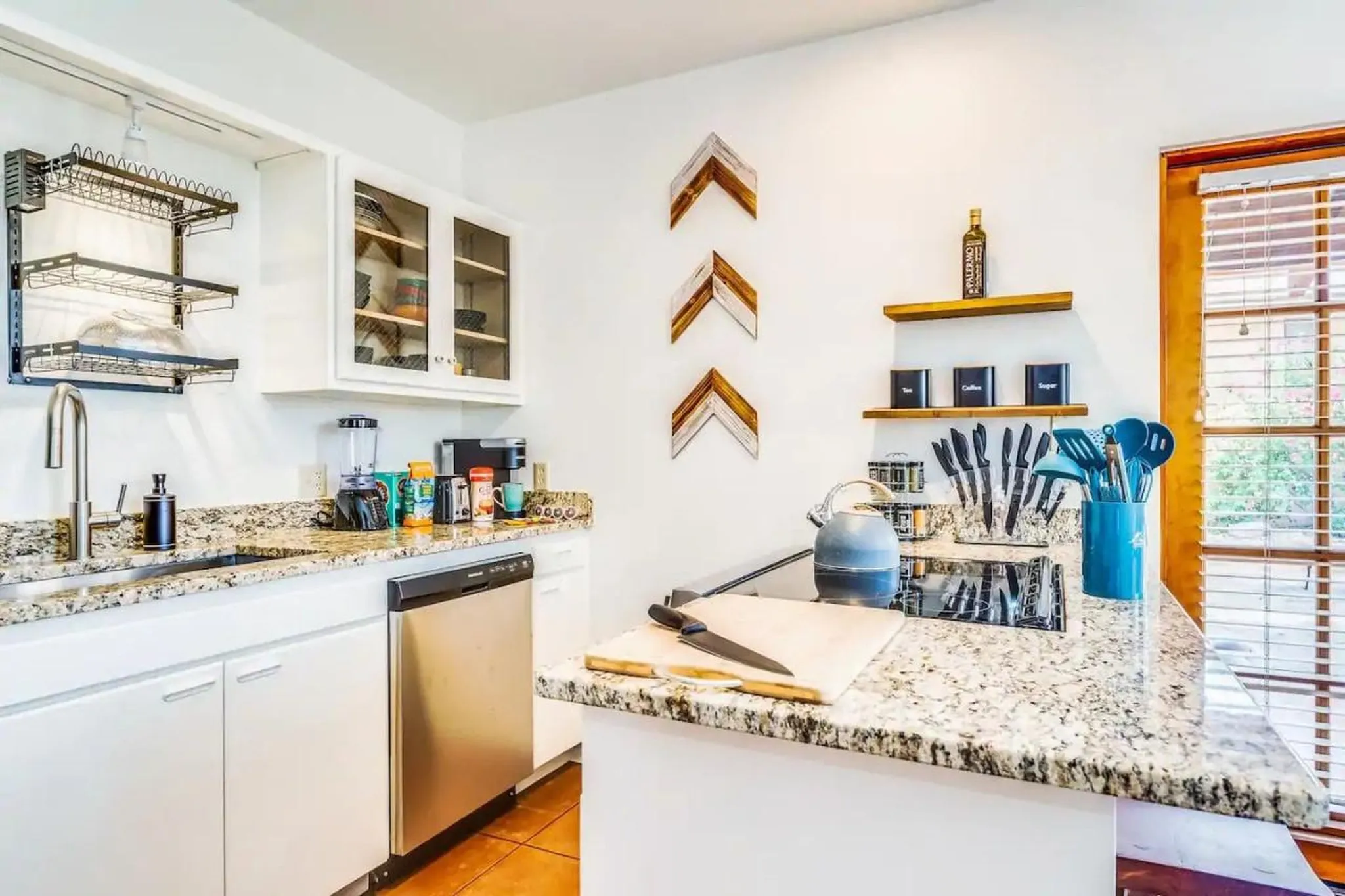 A modern kitchen features white cabinets, granite countertops, and stainless steel appliances.